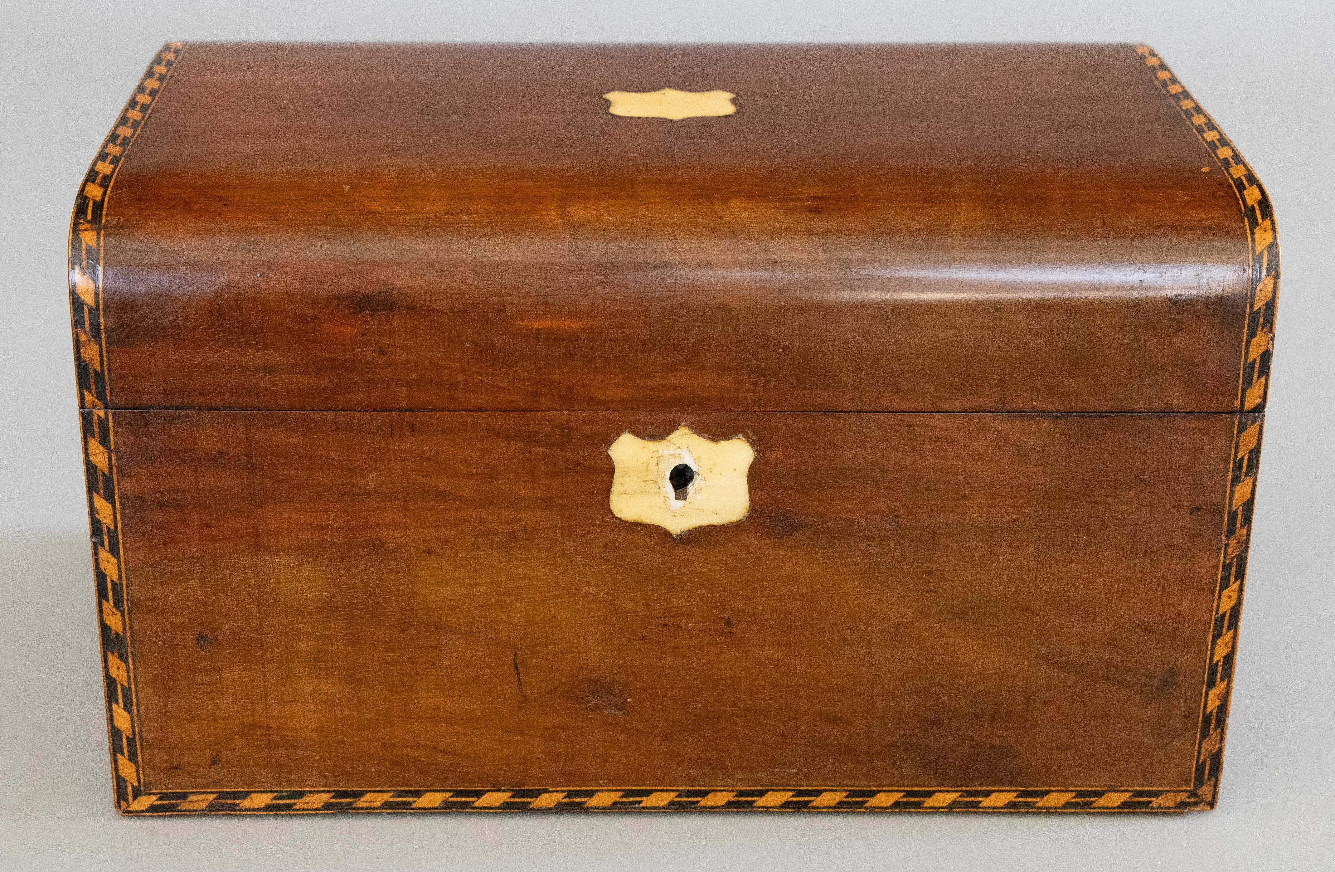 A superb 19th Century English walnut box with lock and key, circa 1870. This fine antique box has a wonderful domed lid accented with tunbridge bands along the edges and a mother of pearl center and key plate. This large hand crafted box has been