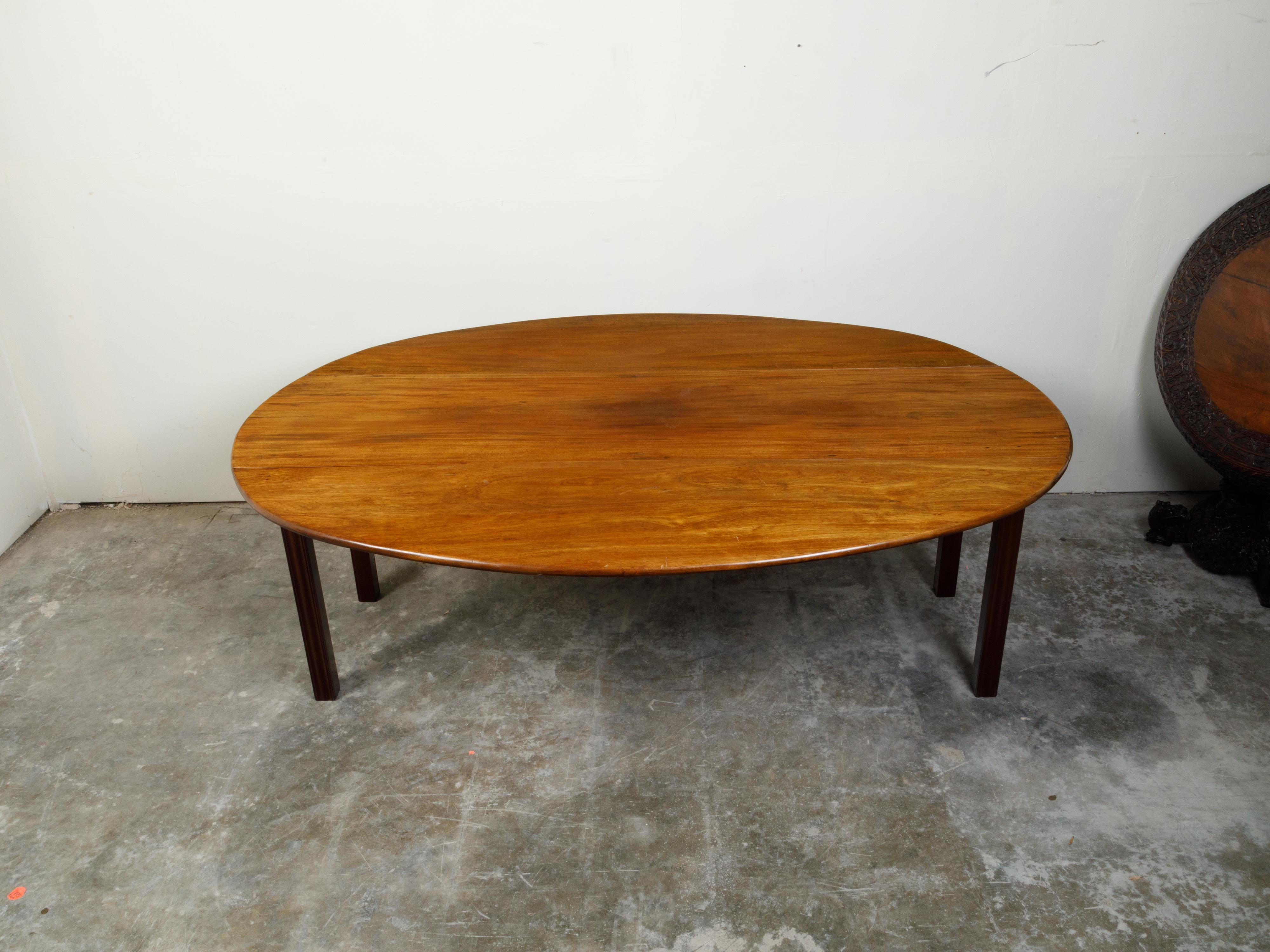 An English walnut drop leaf table from the 19th century, with oval top and straight legs. Created in England during the 19th century, this walnut table features an oval top flanked with two drop leaves, sitting above four straight legs. With its