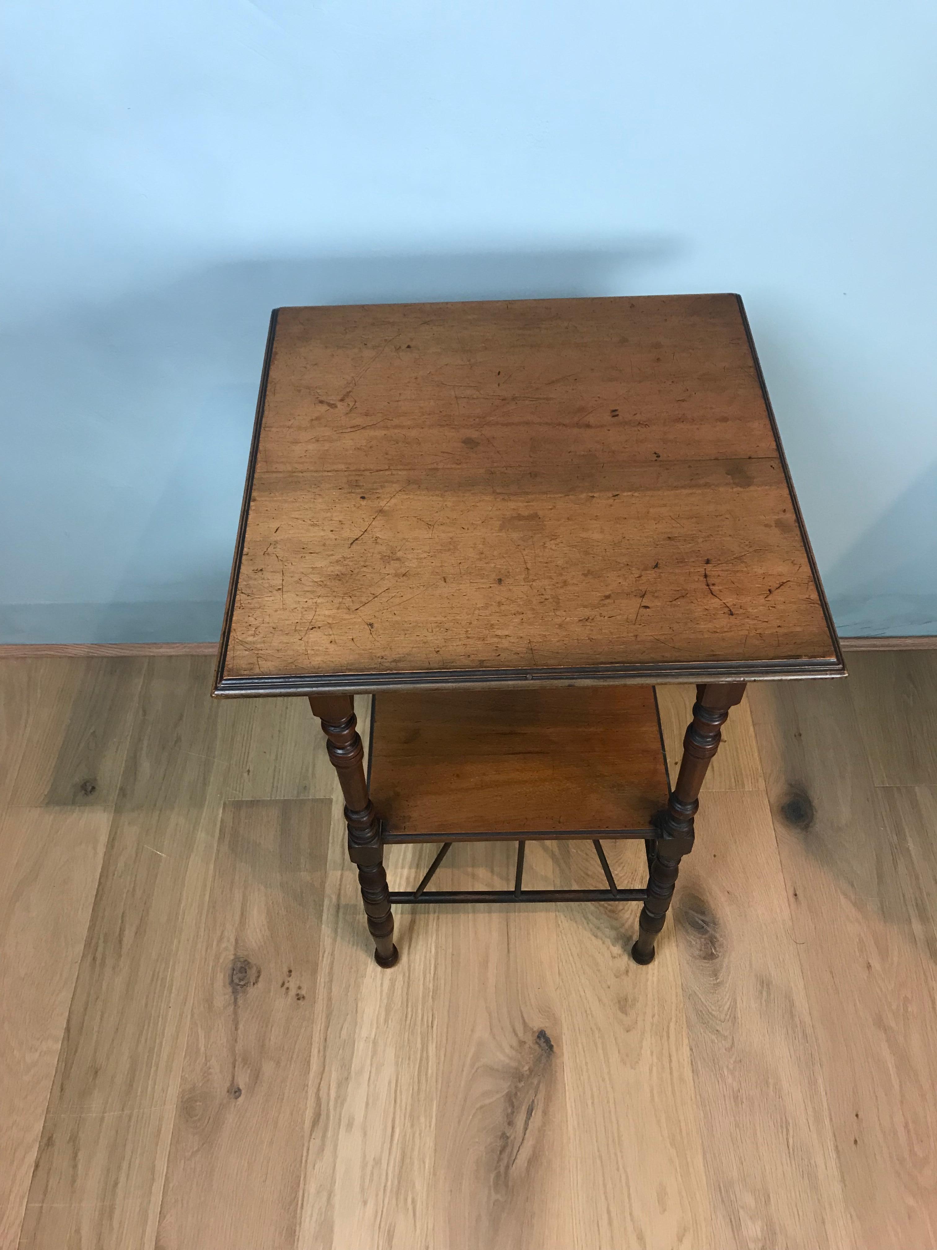 An elegant walnut side table in the manner of Edward William Godwin. Made from walnut, this 19th century occasional or coffee table has a wonderful light honey colour. It features fine turned legs, and lattice bracing beneath the lower tier, which