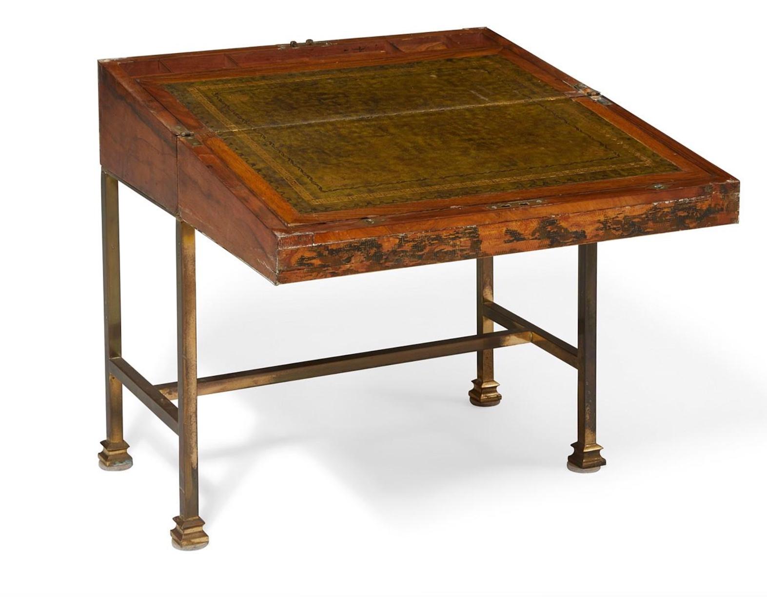 An English brass mounted burr walnut lap desk on later stand from the second half of the 19th century. The hinged lid opening to a double green tooled leather lined writing surface opening to two document compartments, with utensil wells.