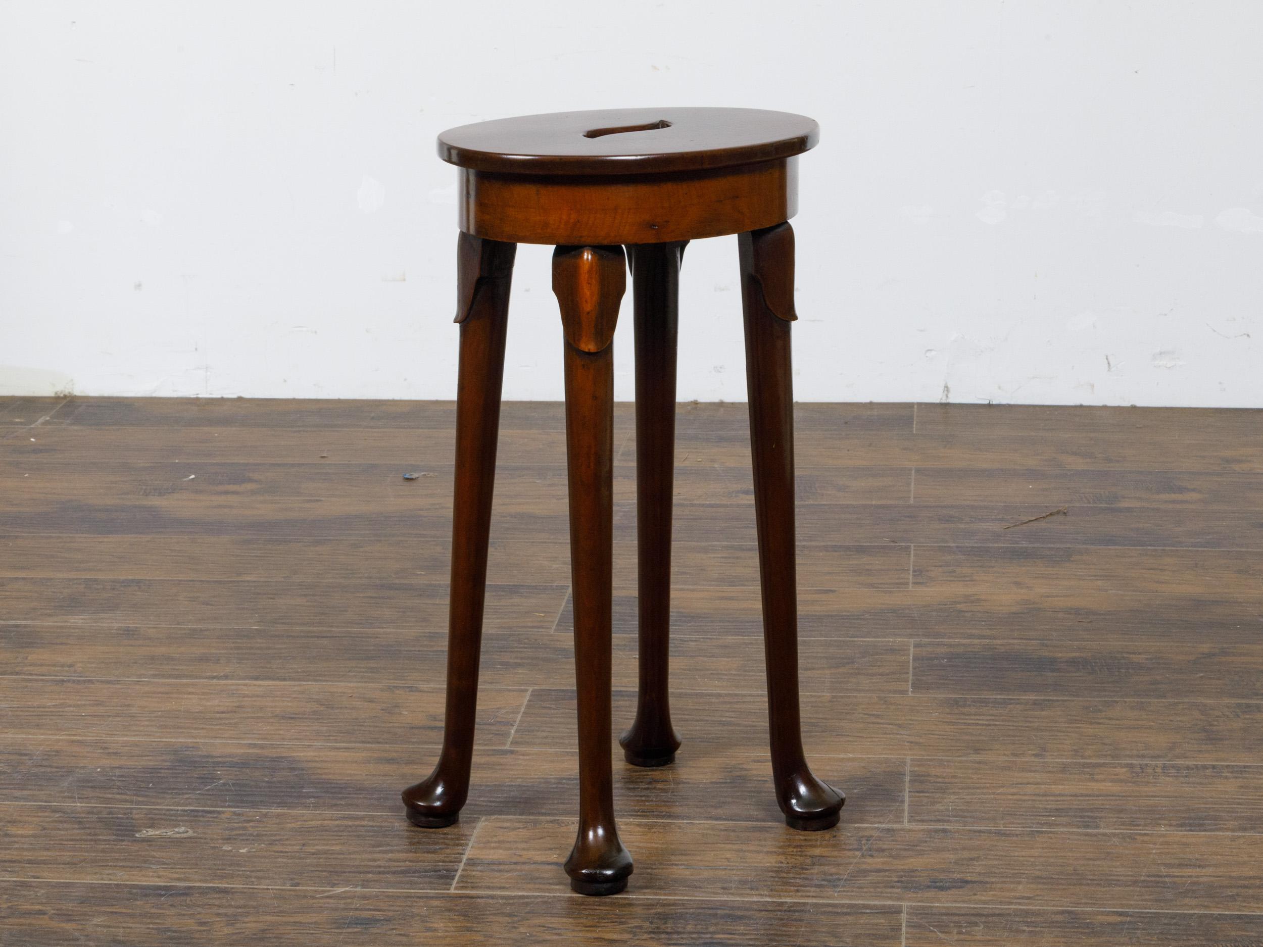 Sgabello inglese in noce del XIX secolo con seduta ovale e maniglia centrale tagliata a mano. Questo affascinante sgabello in noce inglese del XIX secolo presenta un design senza tempo, che unisce funzionalità e sobria eleganza. Realizzata con