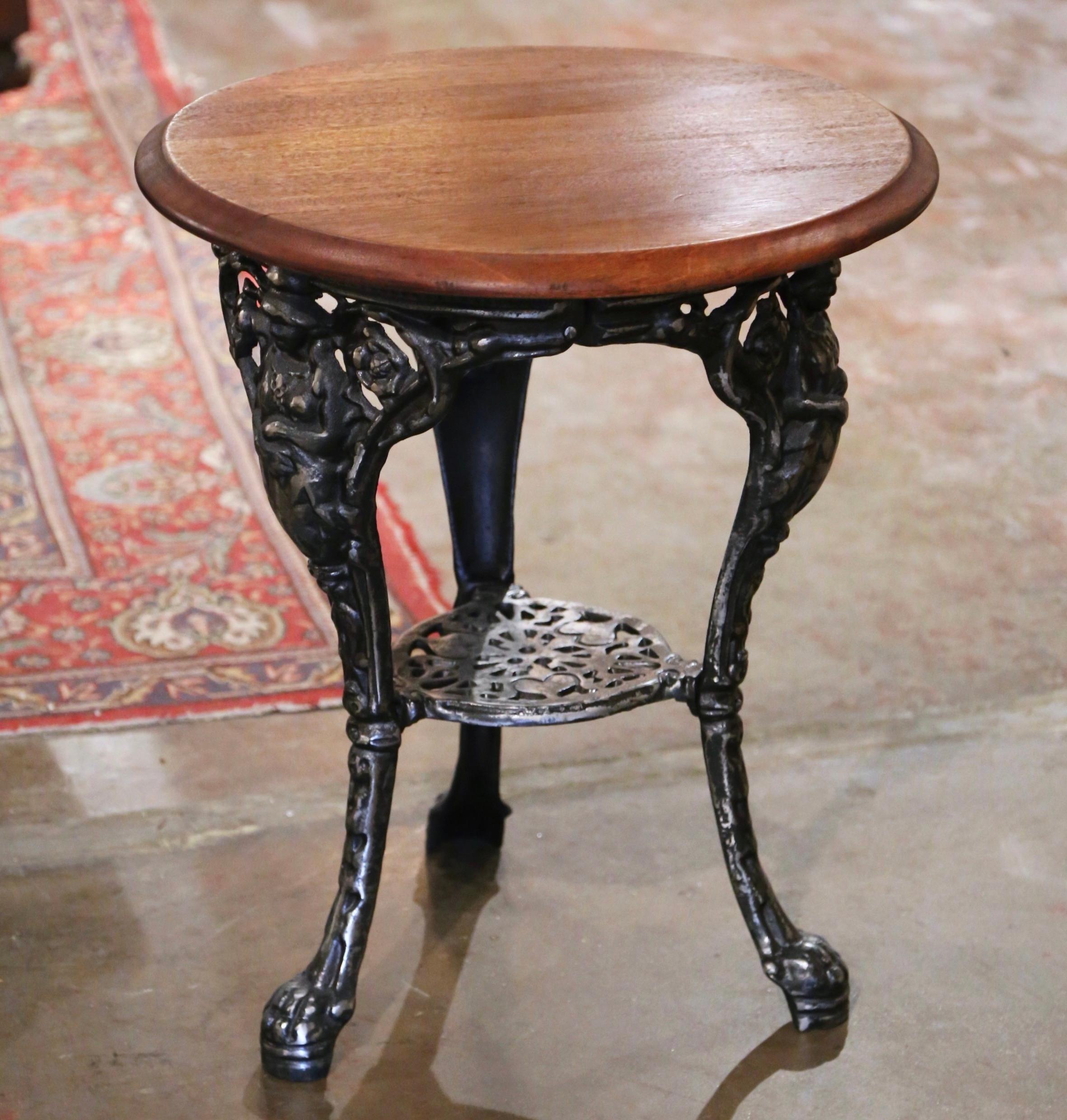 Decorate a covered patio, or sun room with this elegant antique iron and walnut gueridon table. Crafted in England circa 1880, the pub table stands on three cabriole legs ending with paw feet decorated with female figures at the shoulder; the legs