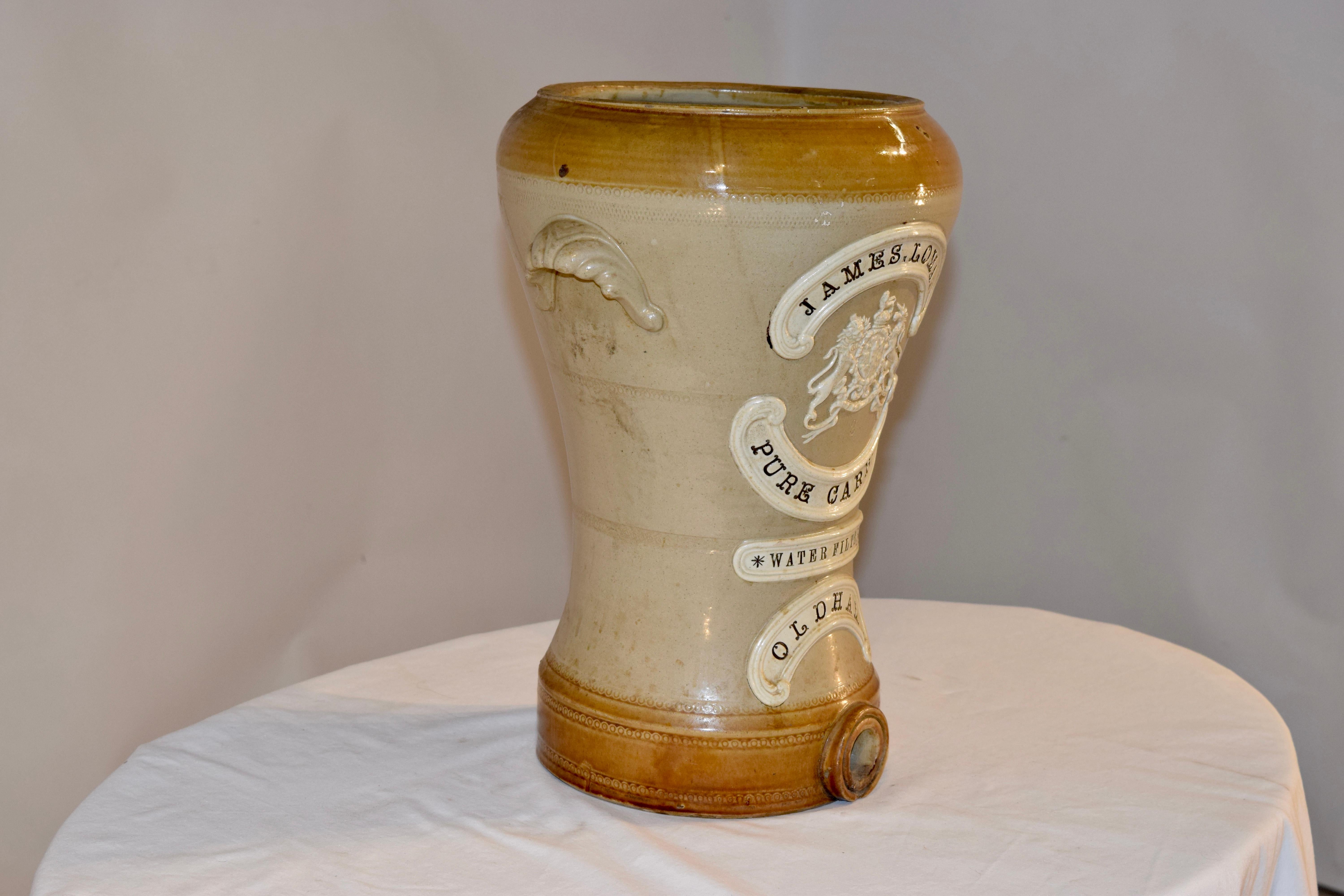 Victorian pure carbon water filter by James Lomas of Oldham. It is made of stoneware and has applied banners with the name James Lomas pure carbon water filter and the town name of Oldham. It has applied handles on the sides and the lid is missing.