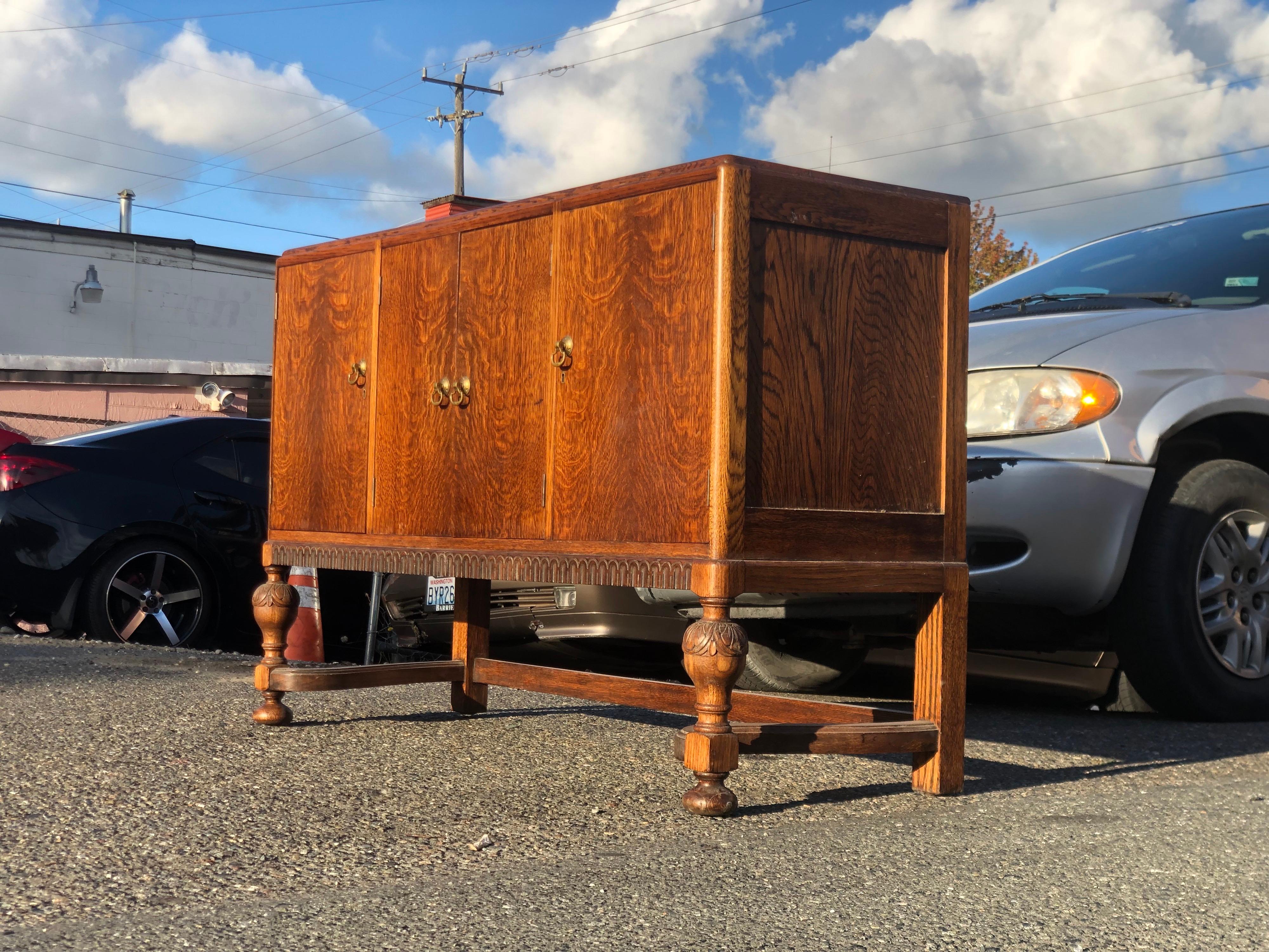 19th Century oak sideboard from England with a round edge around the top, following down to paneled sides with raised geometric panels, flanked by hand-turned applied moldings. The apron is also wonderfully carved and molded for added interest.