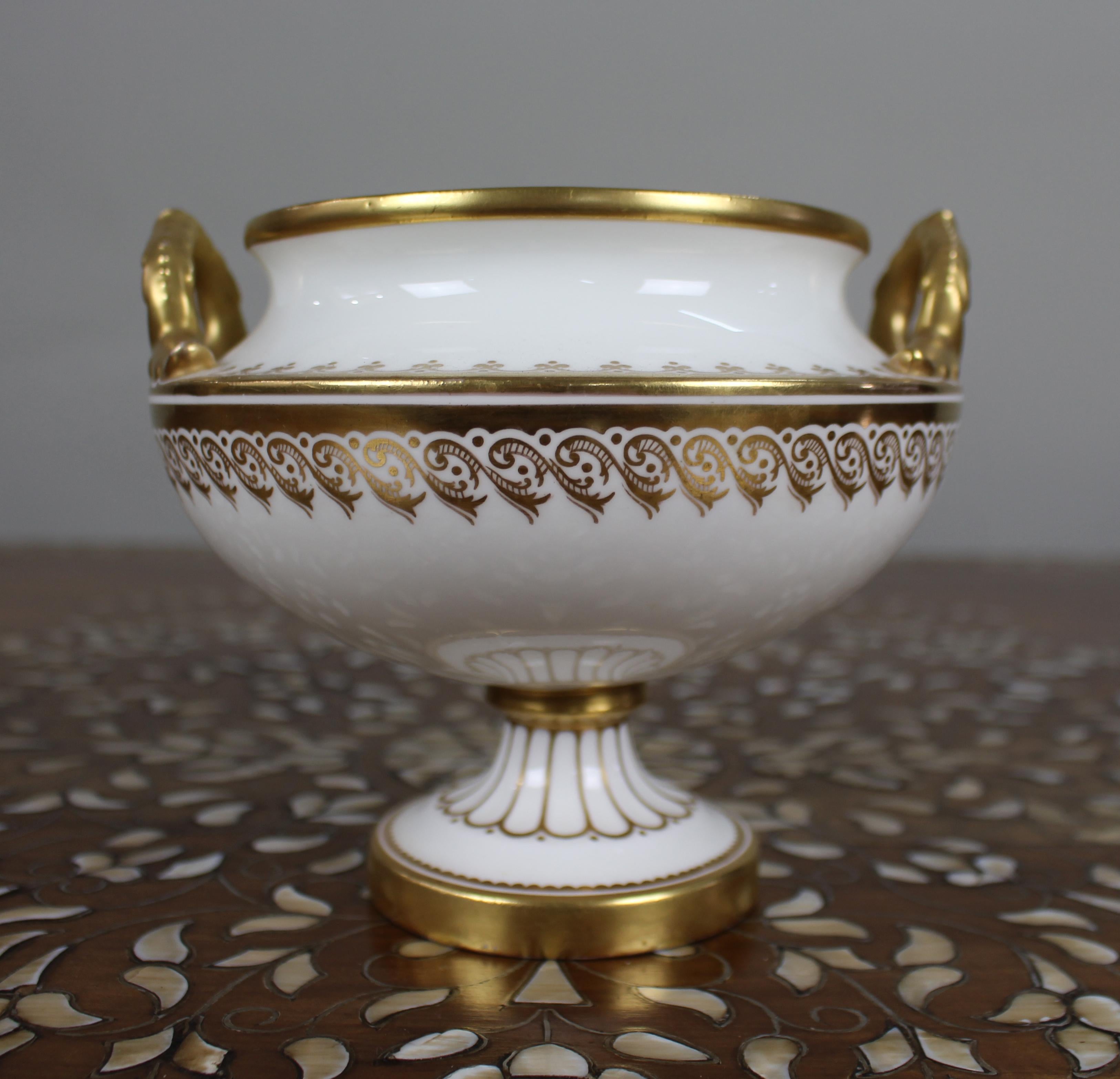 Urne en porcelaine à deux anses, blanche et dorée, du 19e siècle, anglaise

Une urne en porcelaine anglaise de bonne facture datant d'environ 1840, avec un fond blanc et des décorations dorées sur le bord, les poignées et la base. Le design de