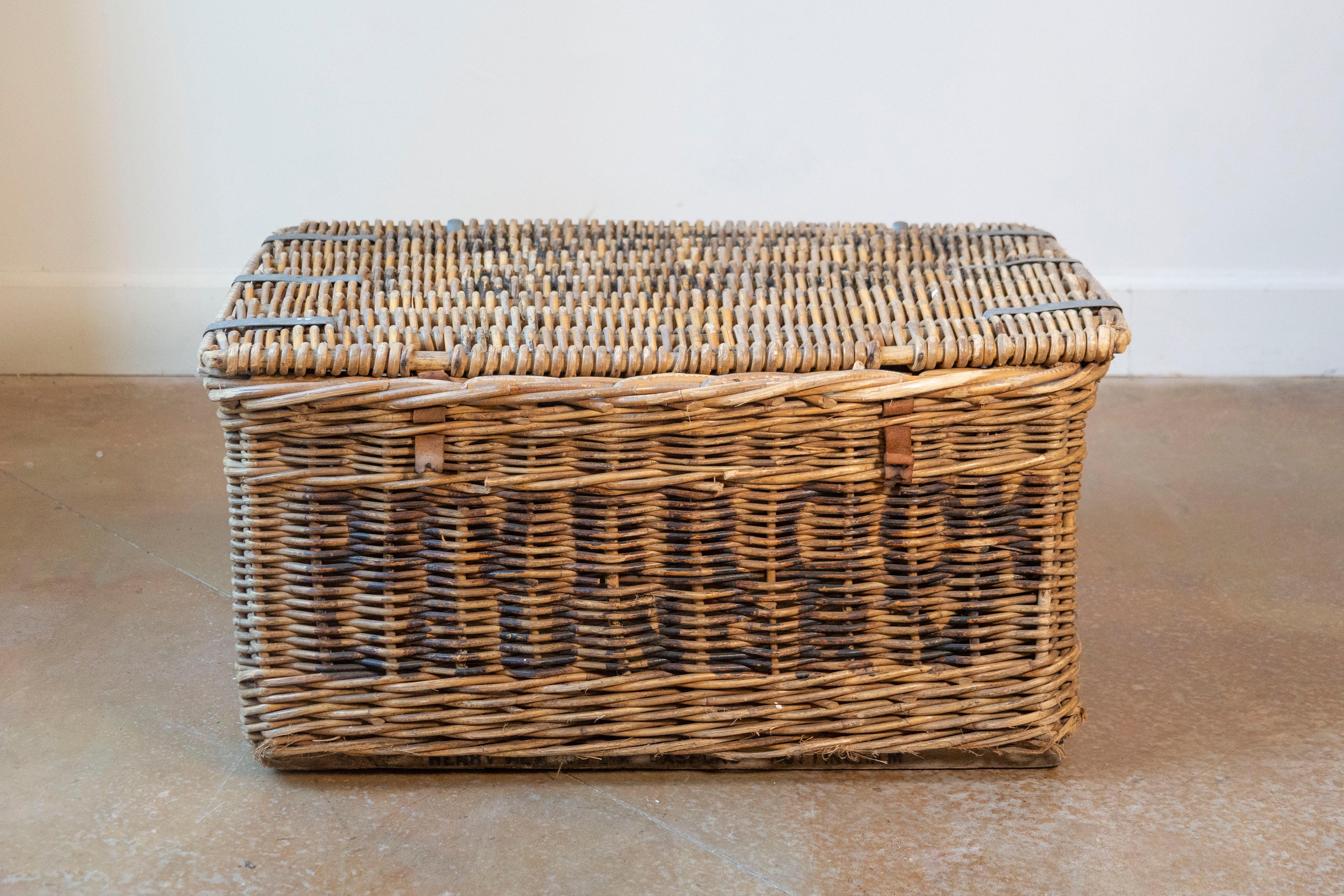 A charming small-scale English wicker basket from the early 20th century, featuring finely handwoven willow construction and original black painted lettering across the front and lid. Though the text has faded over time, its bold, utilitarian