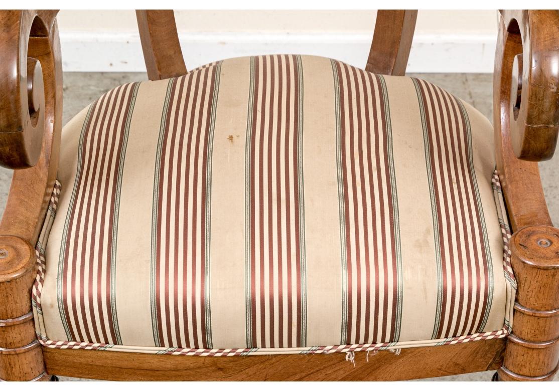 Chaise de capitaine en noyer ancien avec un remarquable cadre en forme de Bol dans une finition générale en noyer miel avec un dossier en forme de baignoire et des accoudoirs à volutes élaborées reposant sur de grands pieds tournés en anneau et en