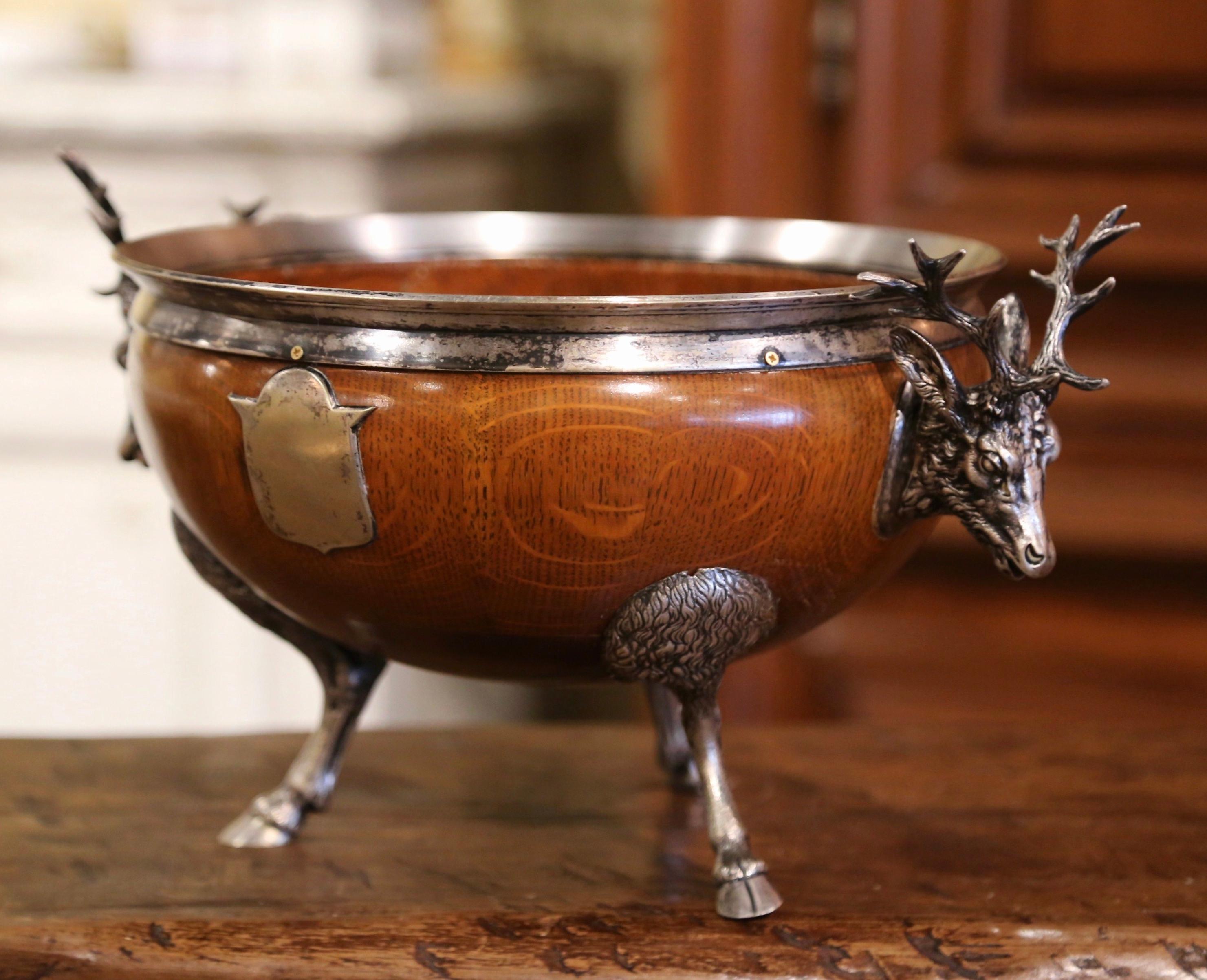 Decorate a dining table or a console with this elegant antique bowl. Crafted in England circa 1880, the round oak dish stands on silver plated hoof feet, and is decorated with stag head figure handles and embellished with a shield on both sides. The