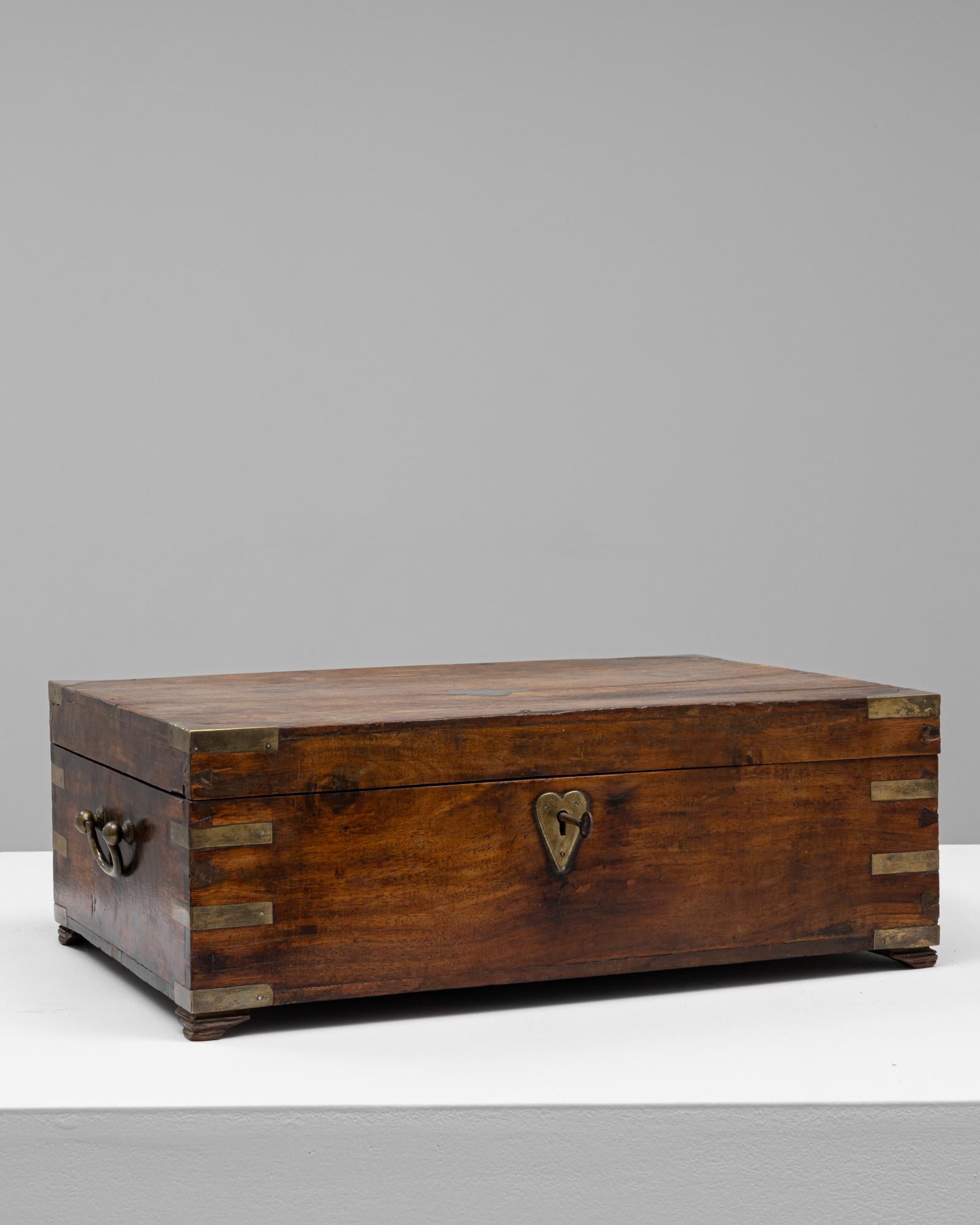 Cette boîte à souvenirs anglaise du XIXe siècle est fabriquée en bois richement teinté et comporte des incrustations de laiton dans les coins pour plus de durabilité et d'attrait décoratif. Son écusson en forme de cœur et sa clé fonctionnelle