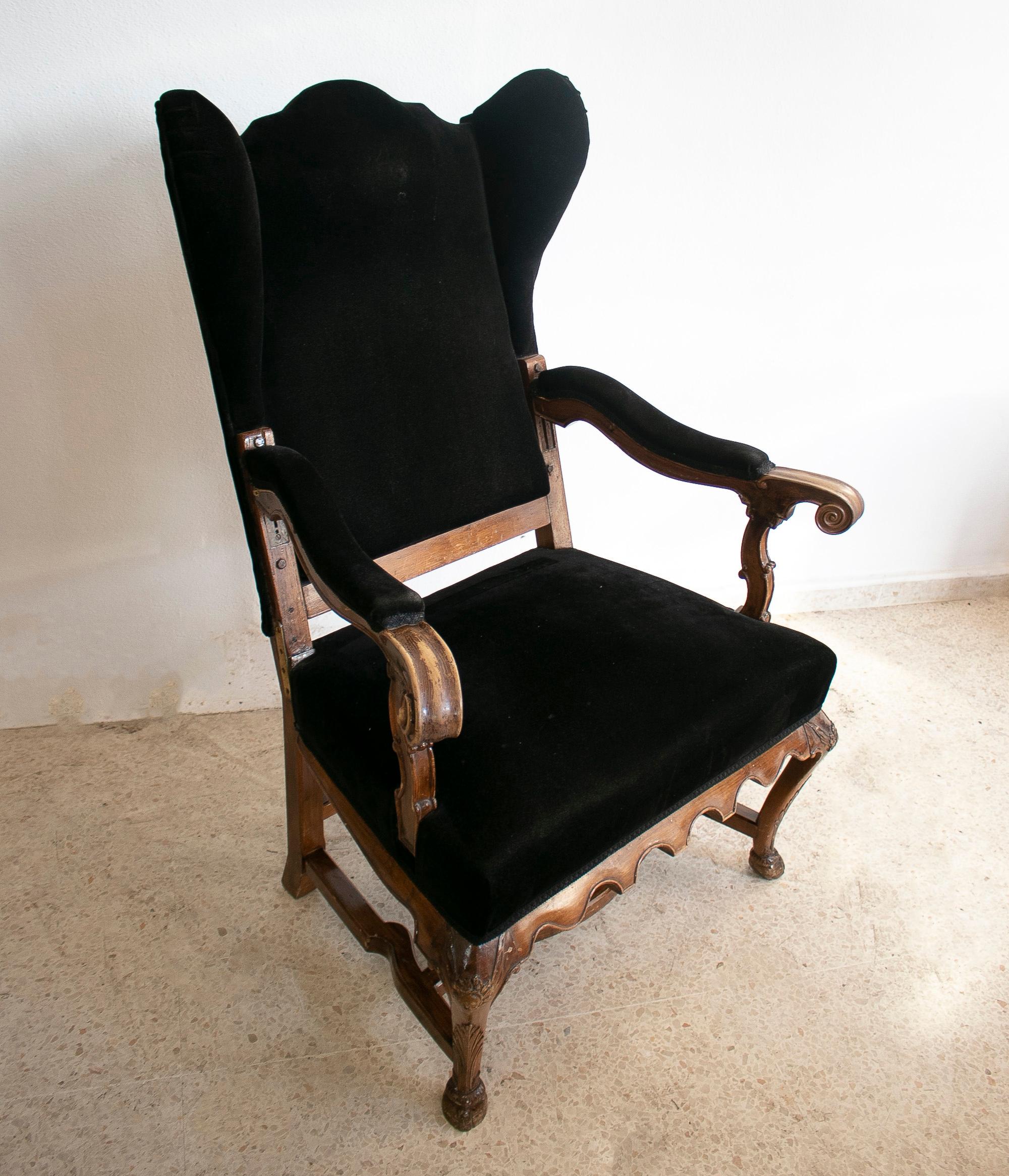 Antique 19th century English wooden winged armchair upholstered with velvet.
  