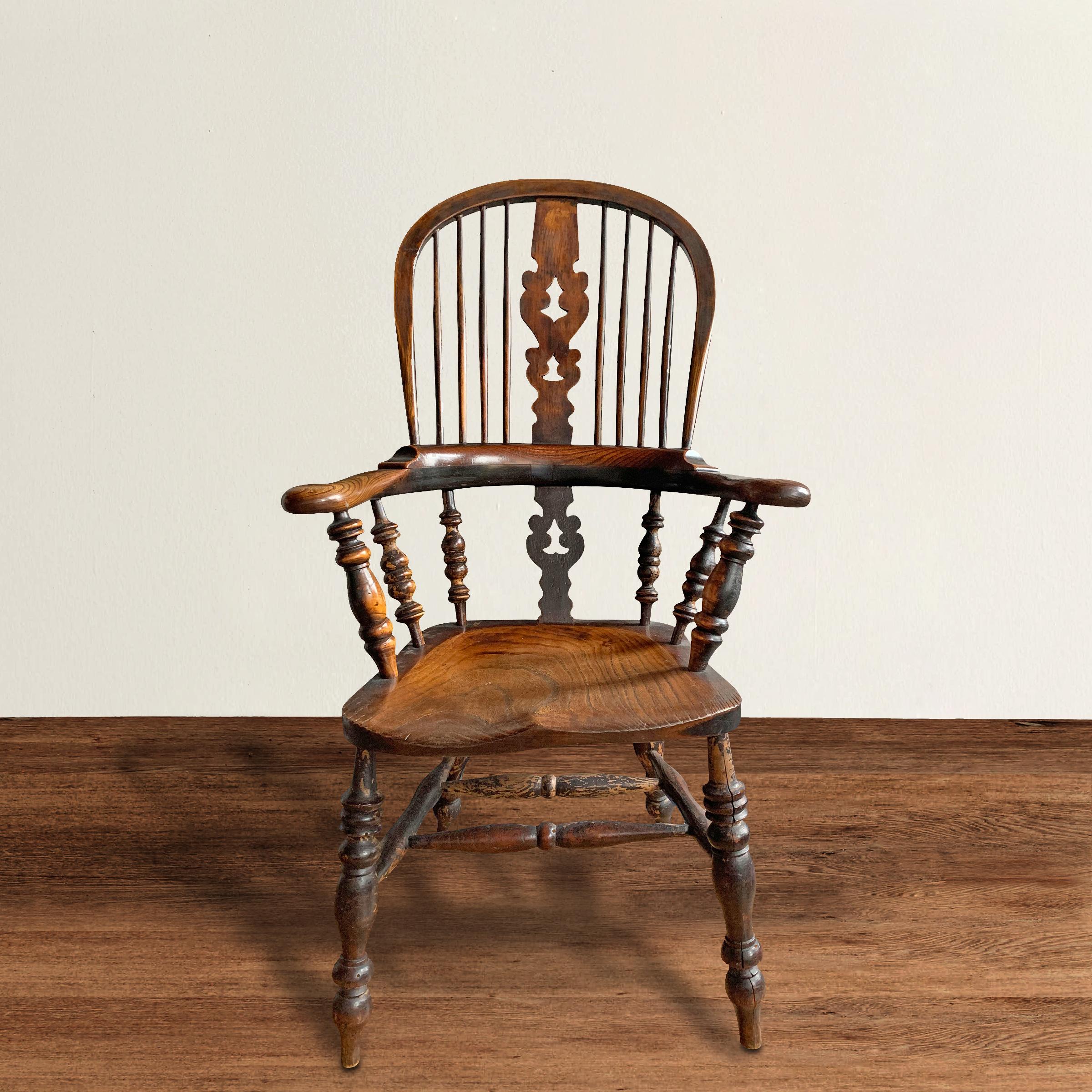 A fantastic mid-19th century English yew wood Windsor armchair with a tall bentwood hoop back, bentwood arms, many turned spindles and legs, a solid plank saddle seat, and a wonderful well-worn patina.