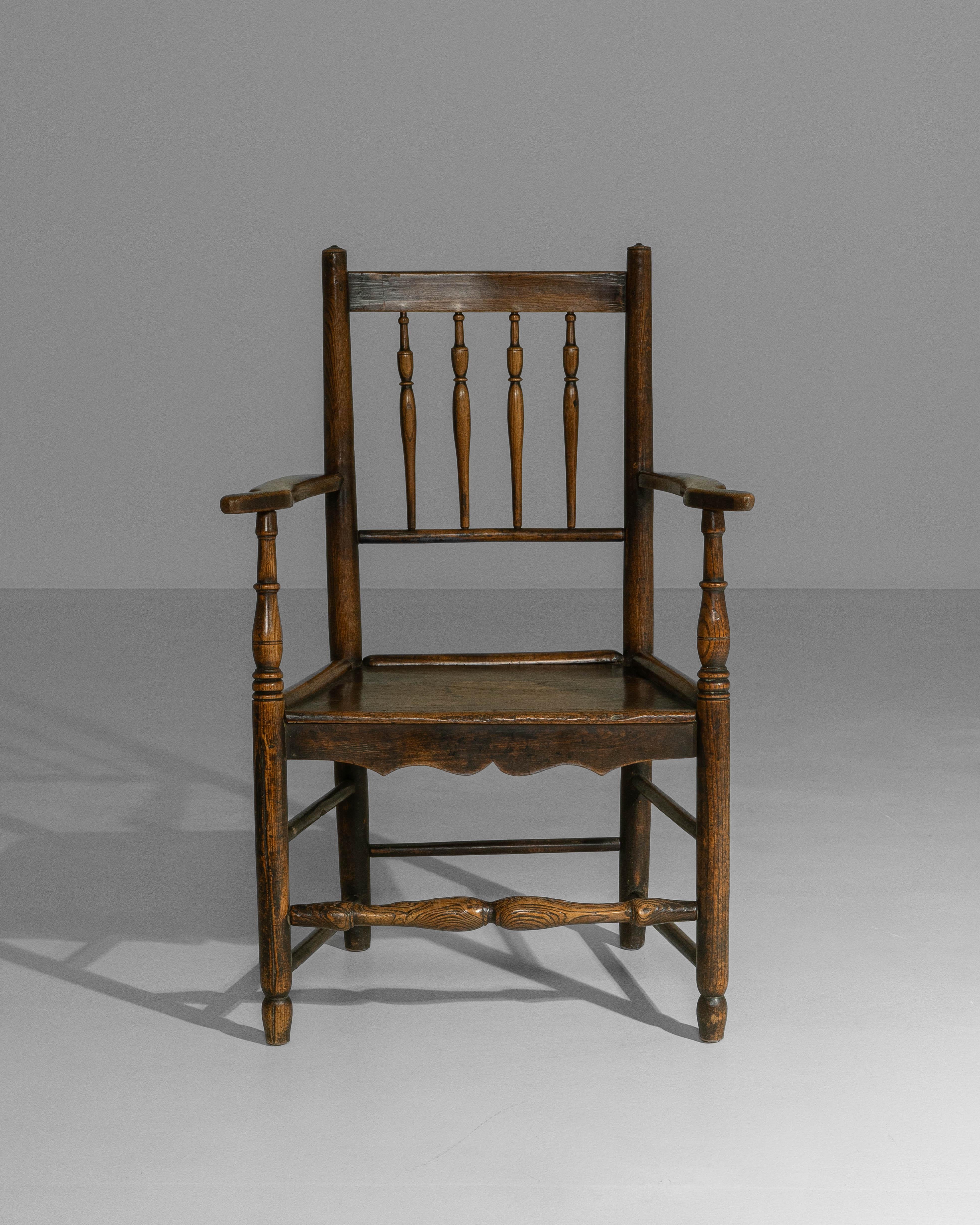 This 19th century English Yorkshire armchair reflects the sturdy construction and restrained ornamentation characteristic of regional craftsmanship. Made from solid oak, the chair features a straight spindle-back with turned verticals framed by