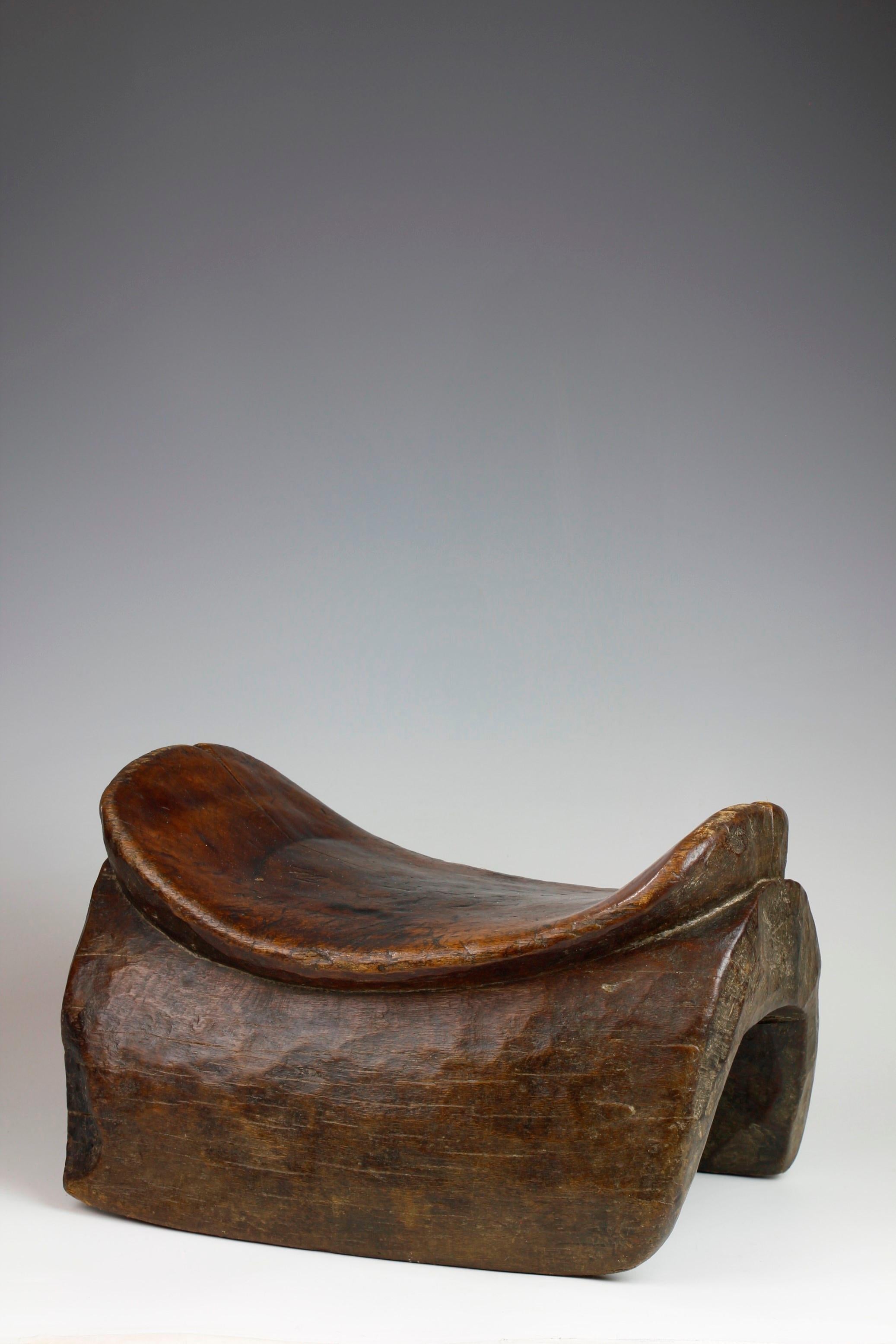 This stool is a beautiful example of an Arsi saddle-shaped stool from the Oromia region of Ethiopia. Finely carved into this form from dense, heavy brown wood, this stool has developed a lovely rich surface patina as a result of use over