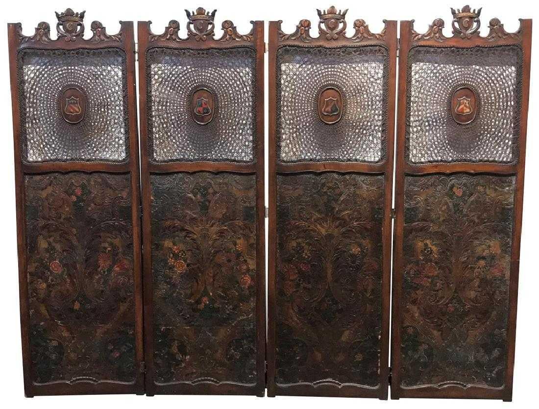 Unique 19th century European armorial four-panel walnut screen with a carved crest bearing leaf scrolls and heraldic coat-of-arms above caned inserts with painted shield accents. Each panel is inset with embossed polychrome leather decorated