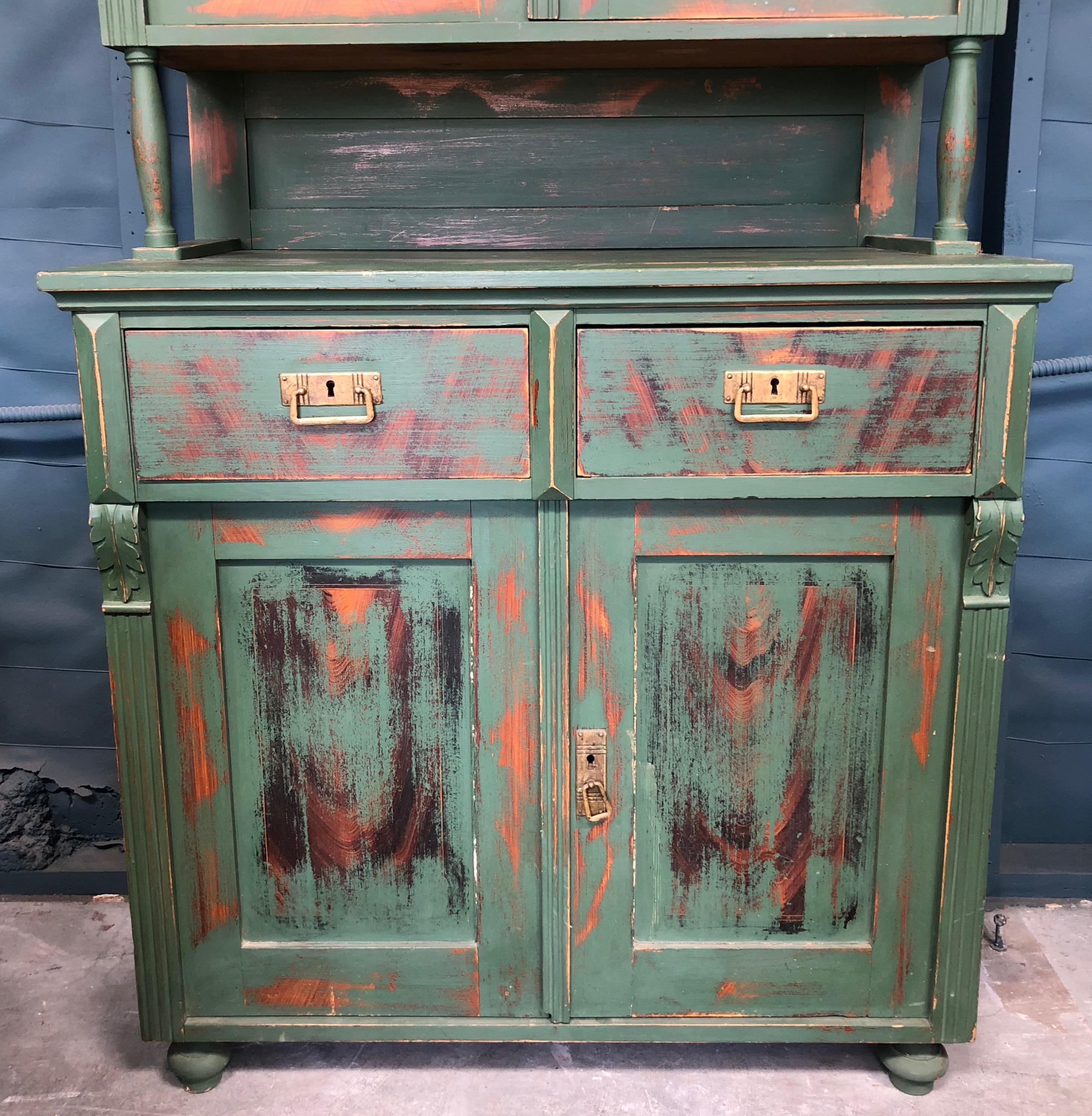 This European hutch is two separate pieces. The top section has two locking glass doors with a shelf inside. The bottom half has two locking wooden doors with a shelf inside. There are, also, two drawers with beautiful bronze pulls.