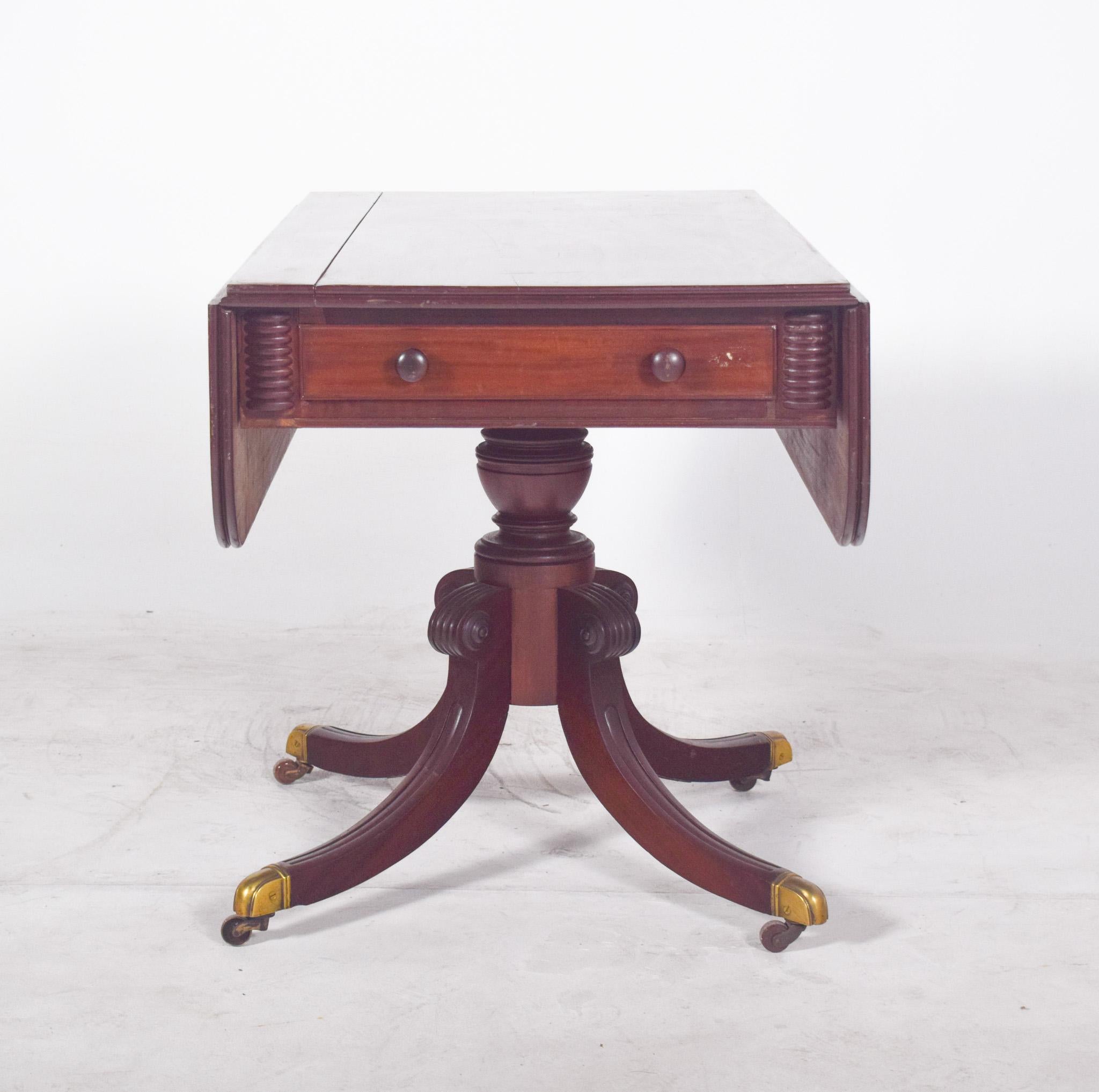 Side table with drawers. With a top that can be extended by means of two folding side flaps, the top has rounded contours and underneath a central drawer with two turned handles. On the sides of the drawer, spiral-carved friezes suggest a careful