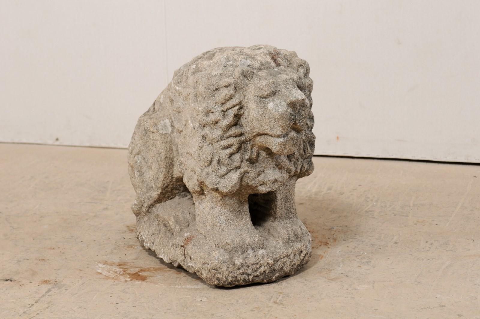 A European carved stone lion from the 19th century, or potentially older. This antique stone lion statute features nice hand carved details, including the nicely textured mane, and facial features. The lion is in a seated position, looking forward,