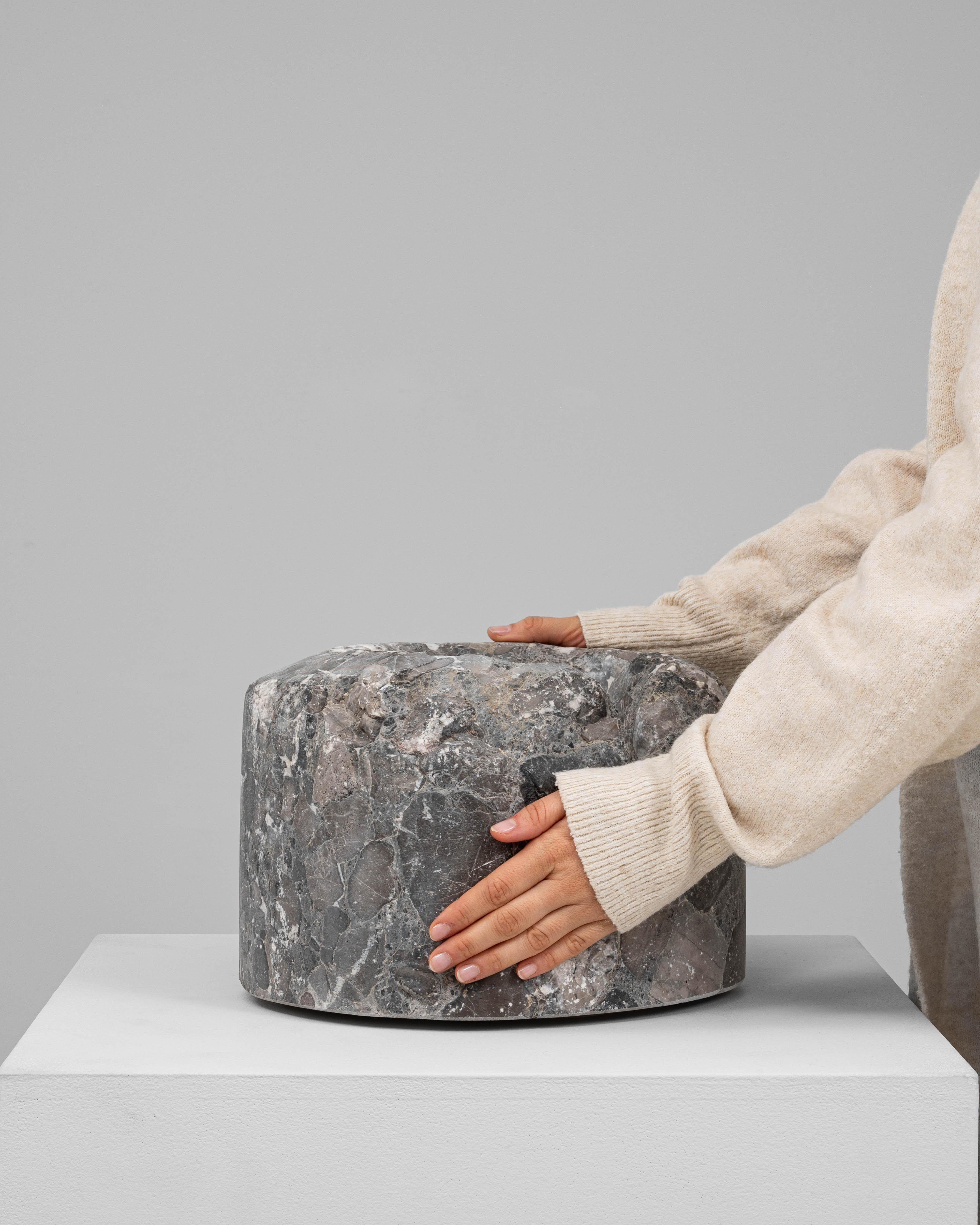 This 19th Century European marble mortar is a commanding and visually rich example of utilitarian craftsmanship. Carved from a unique conglomerate marble, the surface showcases an intricate mosaic of natural stone fragments in deep grays, browns,