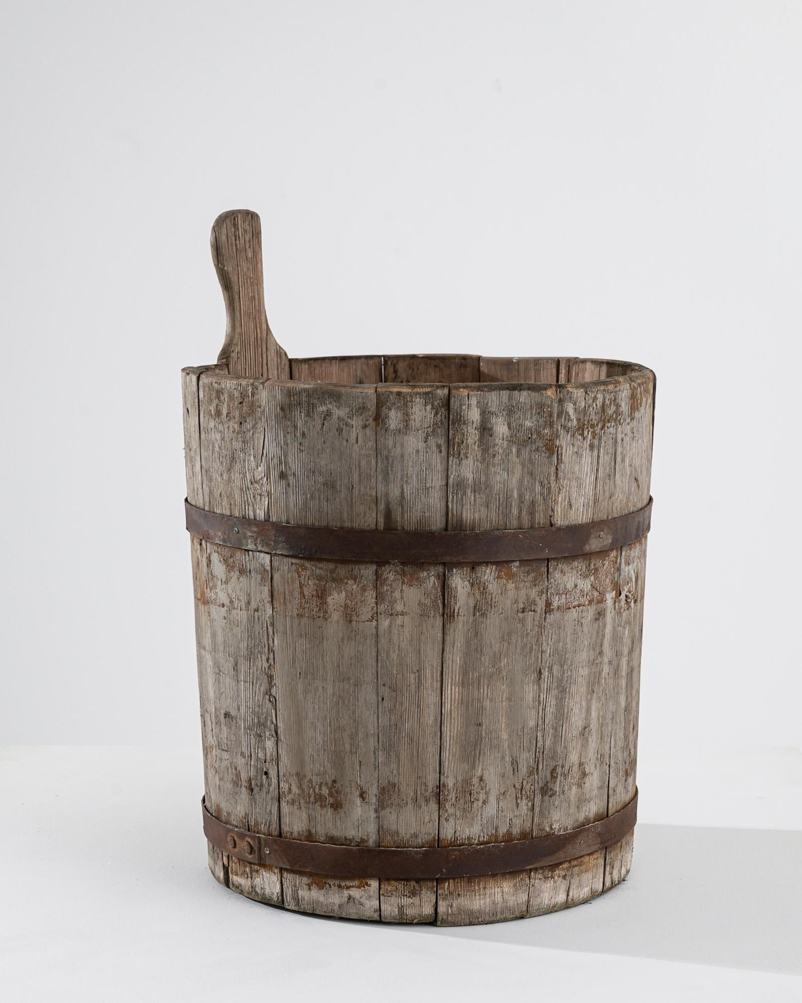 Hewn wooden slats, conjoined by hand-hammered metal bands, this wooden bucket was sourced in Central Europe, dating to the 19th Century. Reminding of a time of hand-made craftsmanship, this rustic accent adds a whisper of history to modern