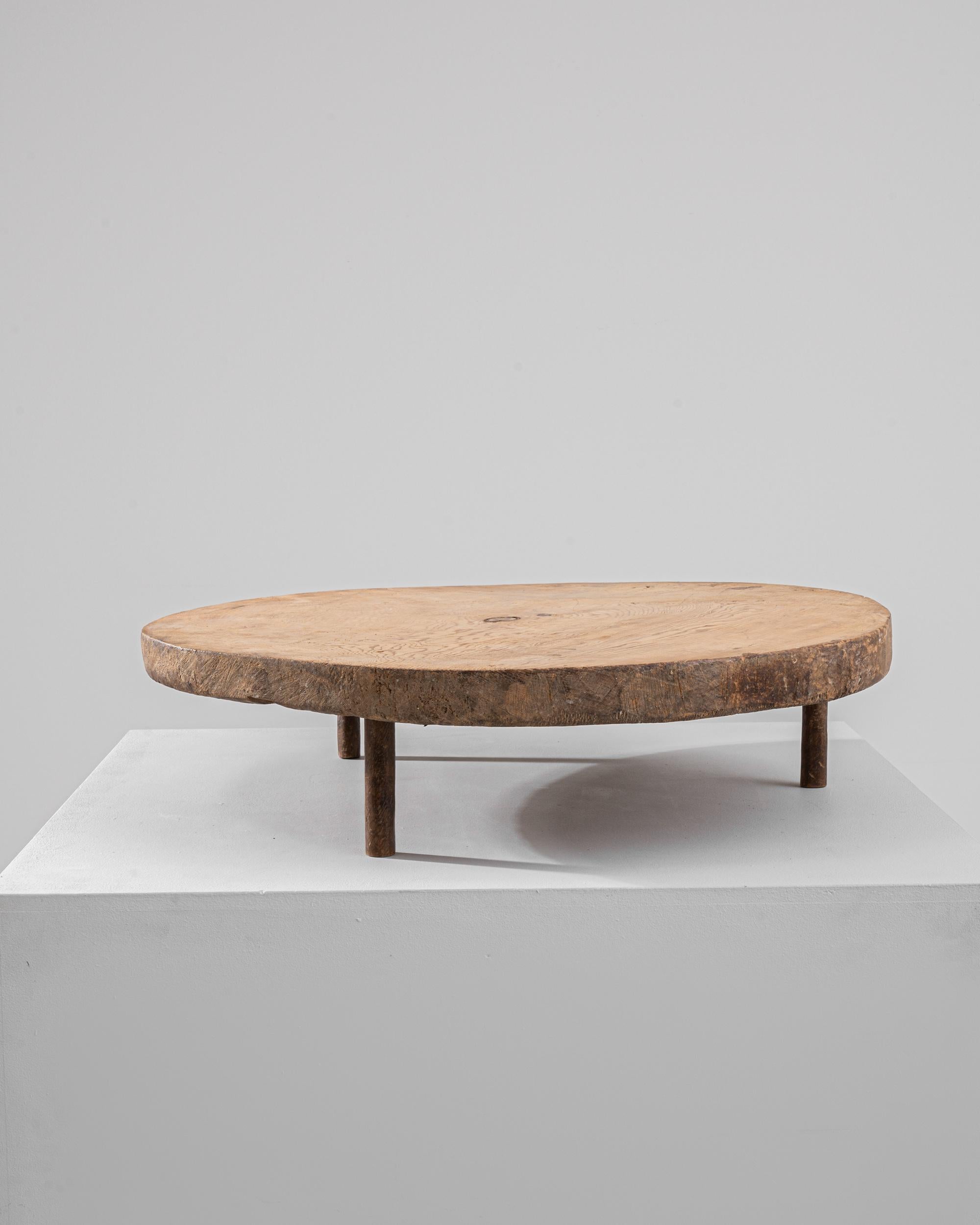 A wooden tray made in Europe during the 19th century. This slab of raw wood has long since been cut and elevated by a trio of round legs. The perfect textural backdrop for serving charcuterie or slicing a beautiful loaf of bread, the distinct grain