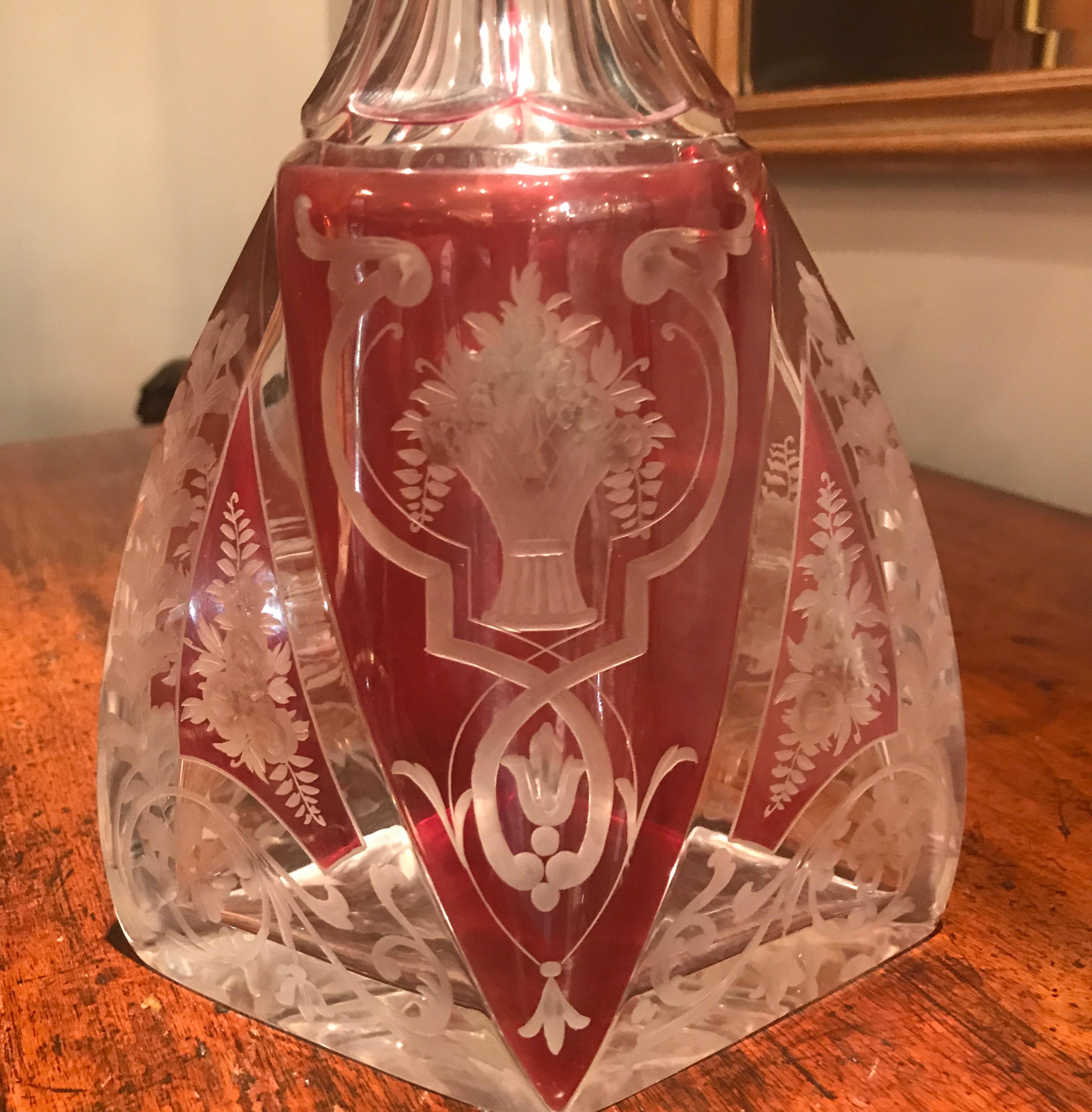 Graceful and elegant intaglio cut-glass tall decanter with original stopper. Panel cut neck with magnificent engraving of floral panels all around. The Violet highlights with a clear cut highly detailed design. Exceptional quality.