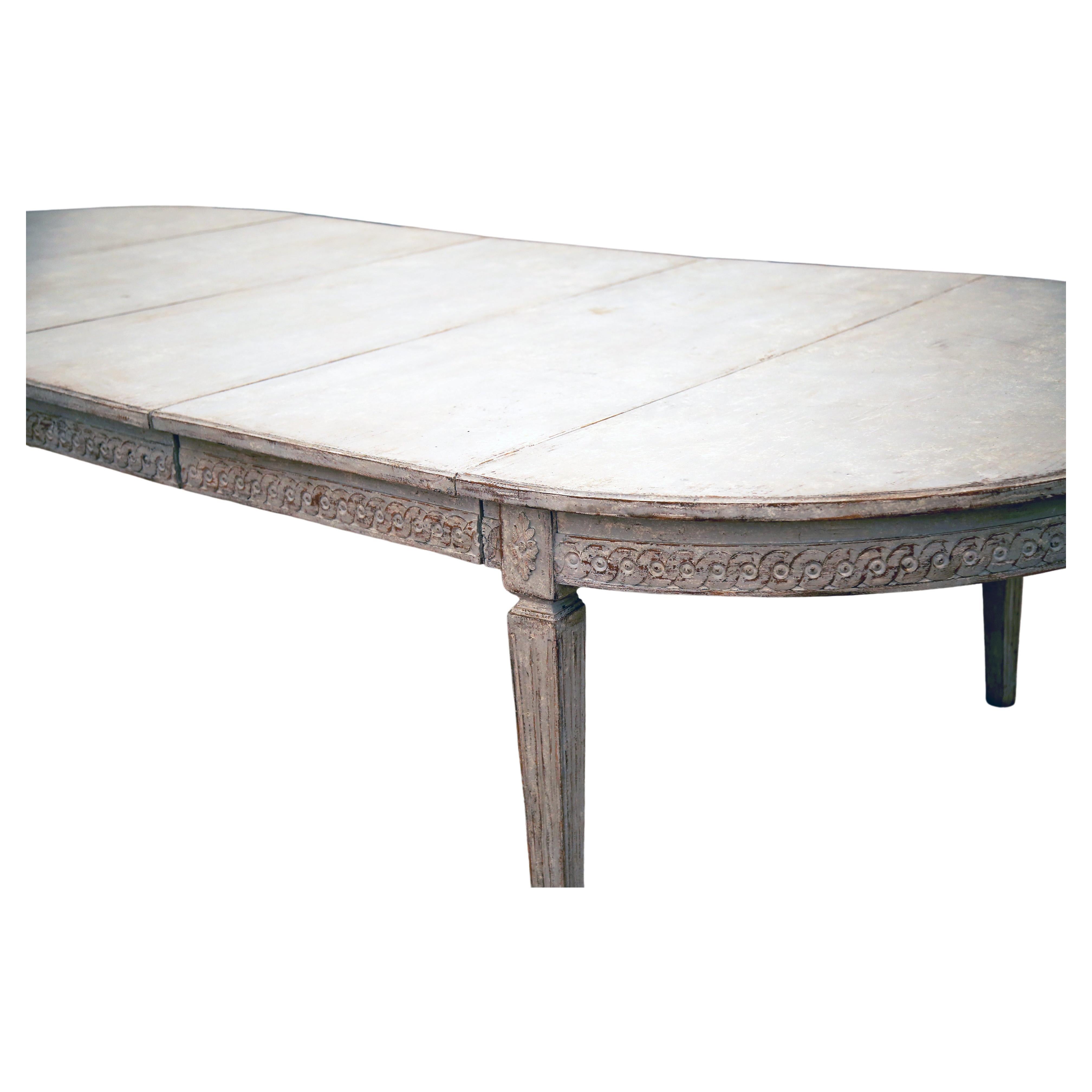 A light-grey and white color palette and finish adorns this stunning and very special antique Swedish Gustavian extendable dining room table. This table is made of hand crafted Pinewood with three leaves that can be adjusted to fit all 3, 2, 1 or