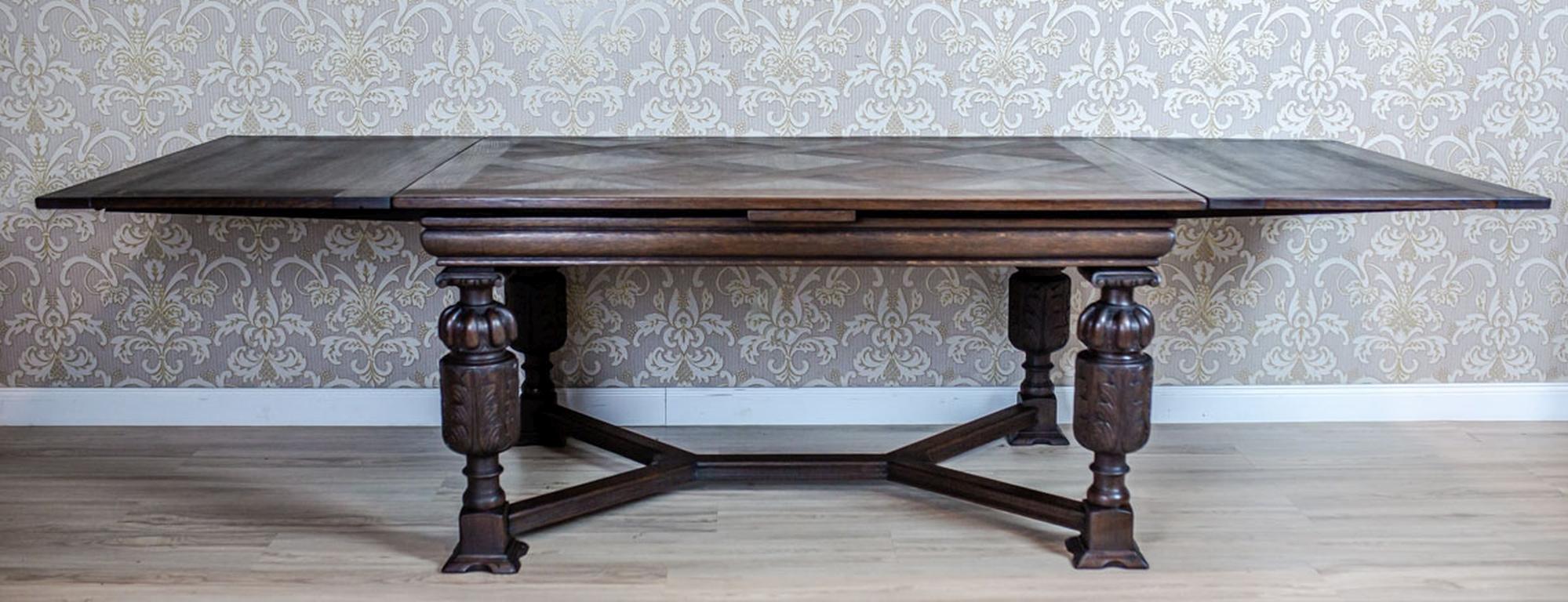 We present you a big antique extendable table made entirely of oakwood.
The top is supported on four rounded legs, which are decorated with carved patterns and connected with Y-shaped stretchers.

This table is after renovation and has been