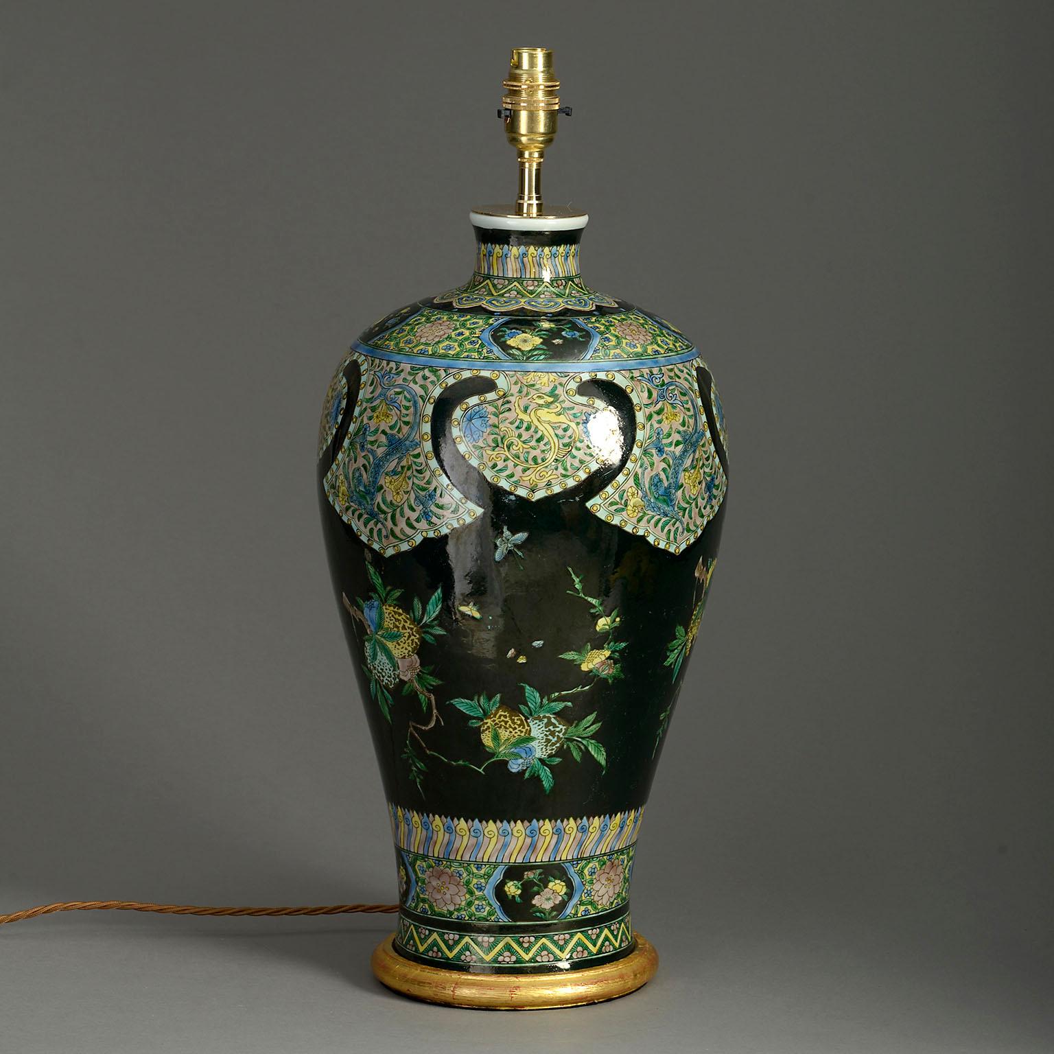 Vase en porcelaine de la famille noire de la fin du XIXe siècle, décoré de papillons et d'arbres fruitiers en abondance dans des glaçures polychromes. Maintenant monté comme une lampe de table avec une base en bois doré tournée à la main.

Les