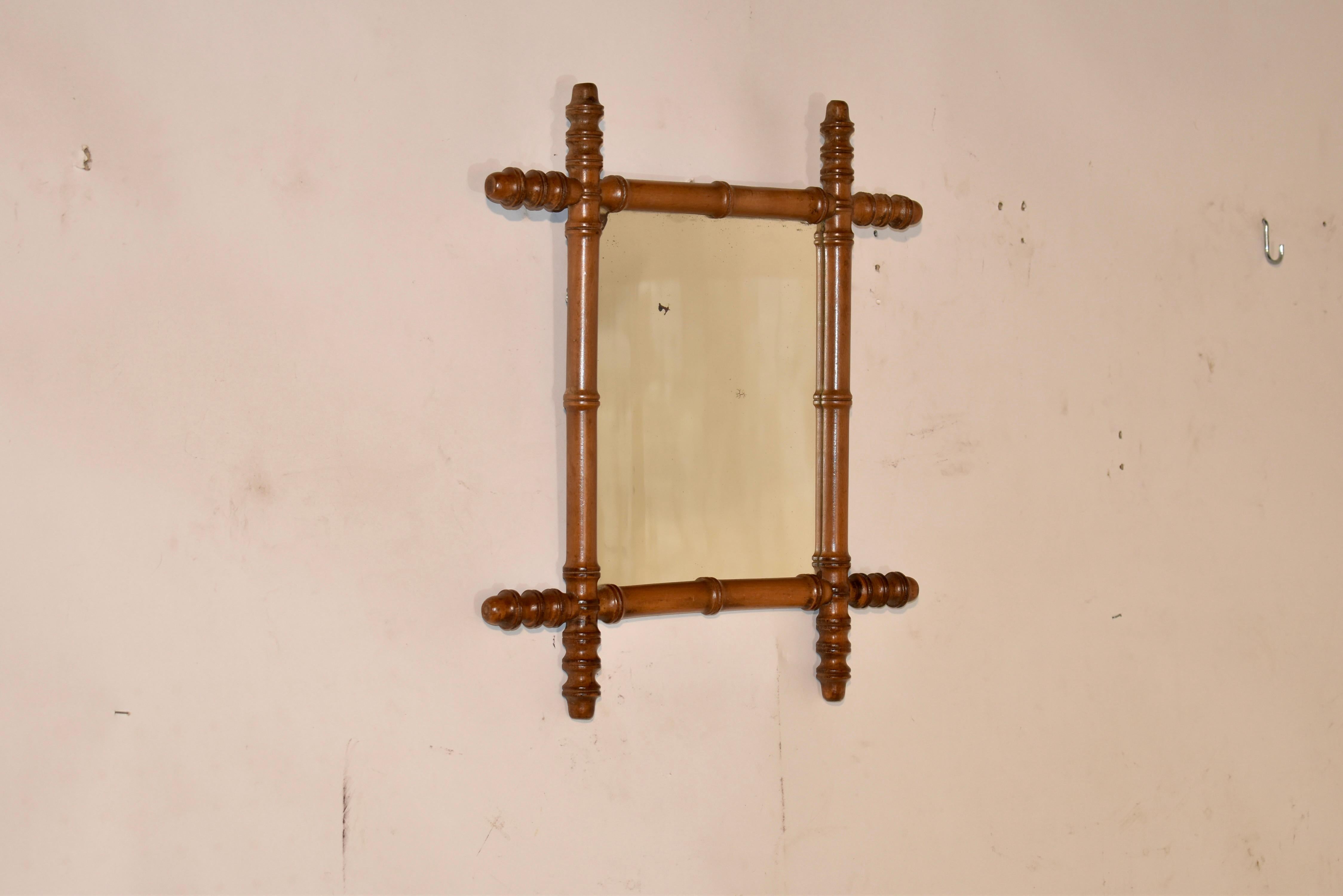 19th century cherry mirror from France. The frame is made from cherry and its hand turned to look like bamboo. The frame is surrounding a mirror, which appears to be original. The mirror is worn, as is normal for a mirror of this age, and has loss