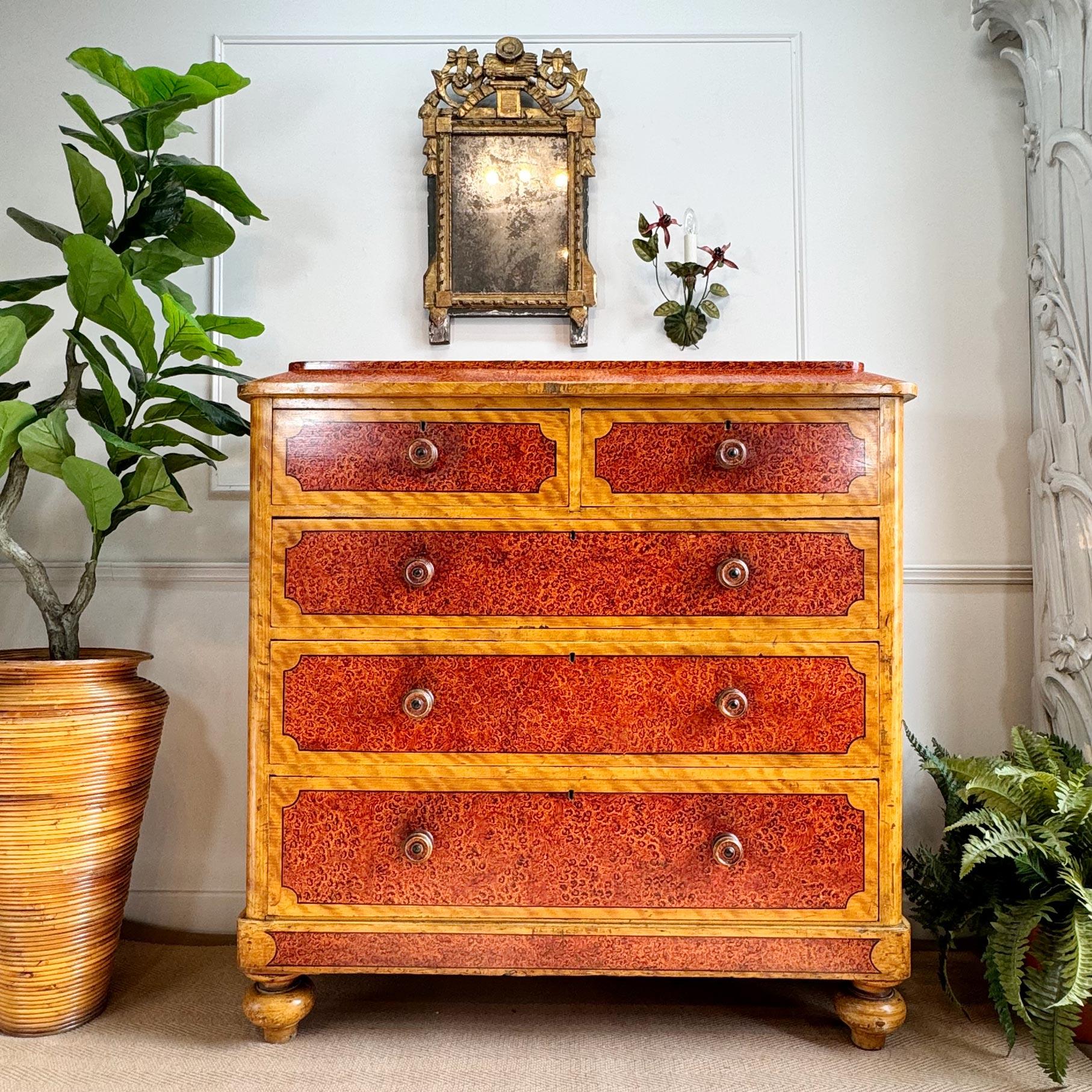 An impressive chest of pine drawers from the mid-19th century, hand decorated with linework and a scumble & faux burlwood pattern, on raised tapered bun feet, two over three drawer composition, complete with the original decorative