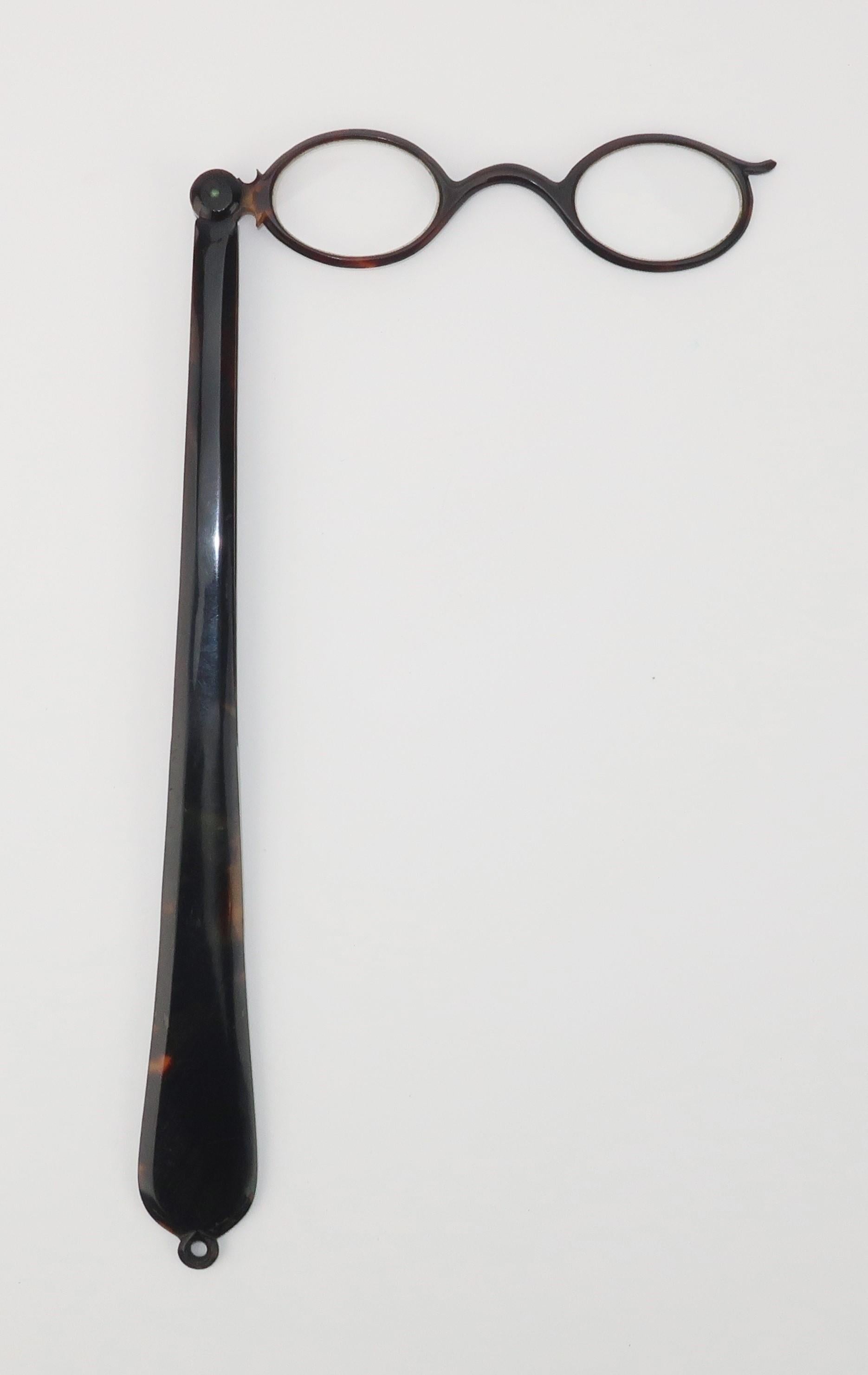 Late 19th Century imitation tortoise shell lorgnette magnifier glasses with a dramatic foldable long handle.  A ring at the end of the handle can be used to attach the lorgnette to a chain for easy wear.  Perfect for a dapper gent or a lady of