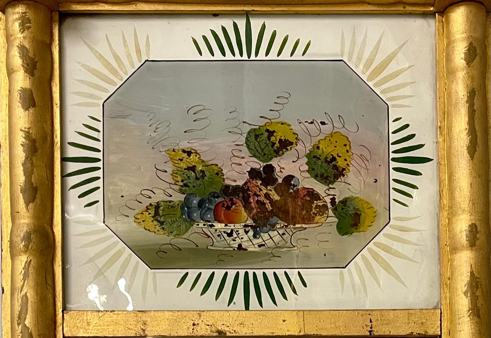19th century federal eglomise decorated wall or table mirror having a wonderfully gilt decorated frame under an eglomise glass panel depicting a basket of fruit. Can easily be used on top of any table or vanity if placed on a stand.