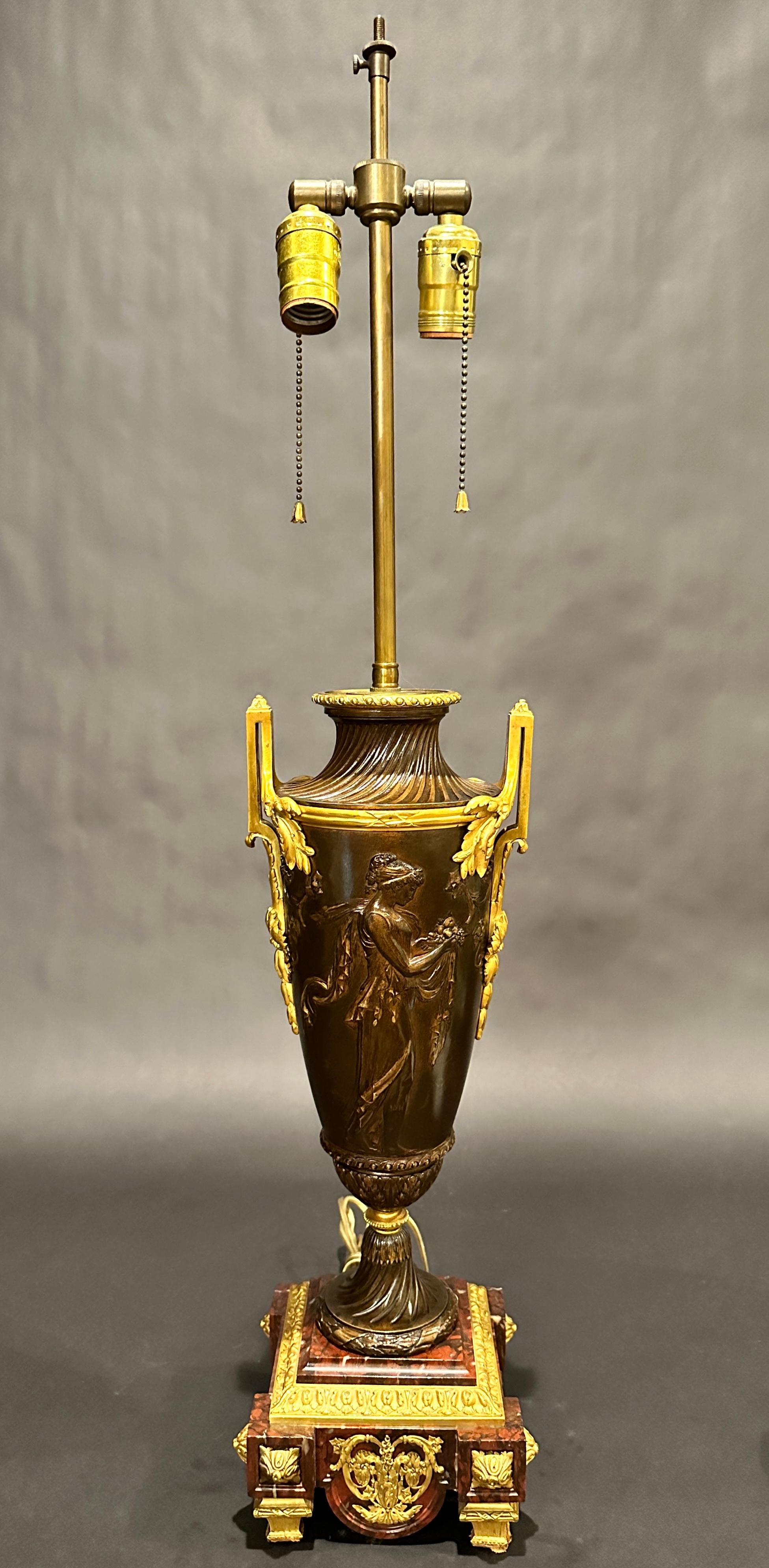 Antique 19th century patinated urn with gilt handles mounted on a rouge marble stepped base adorned with finely cast gilt mounts. Urn designed with classical women with fruit and wine.
20