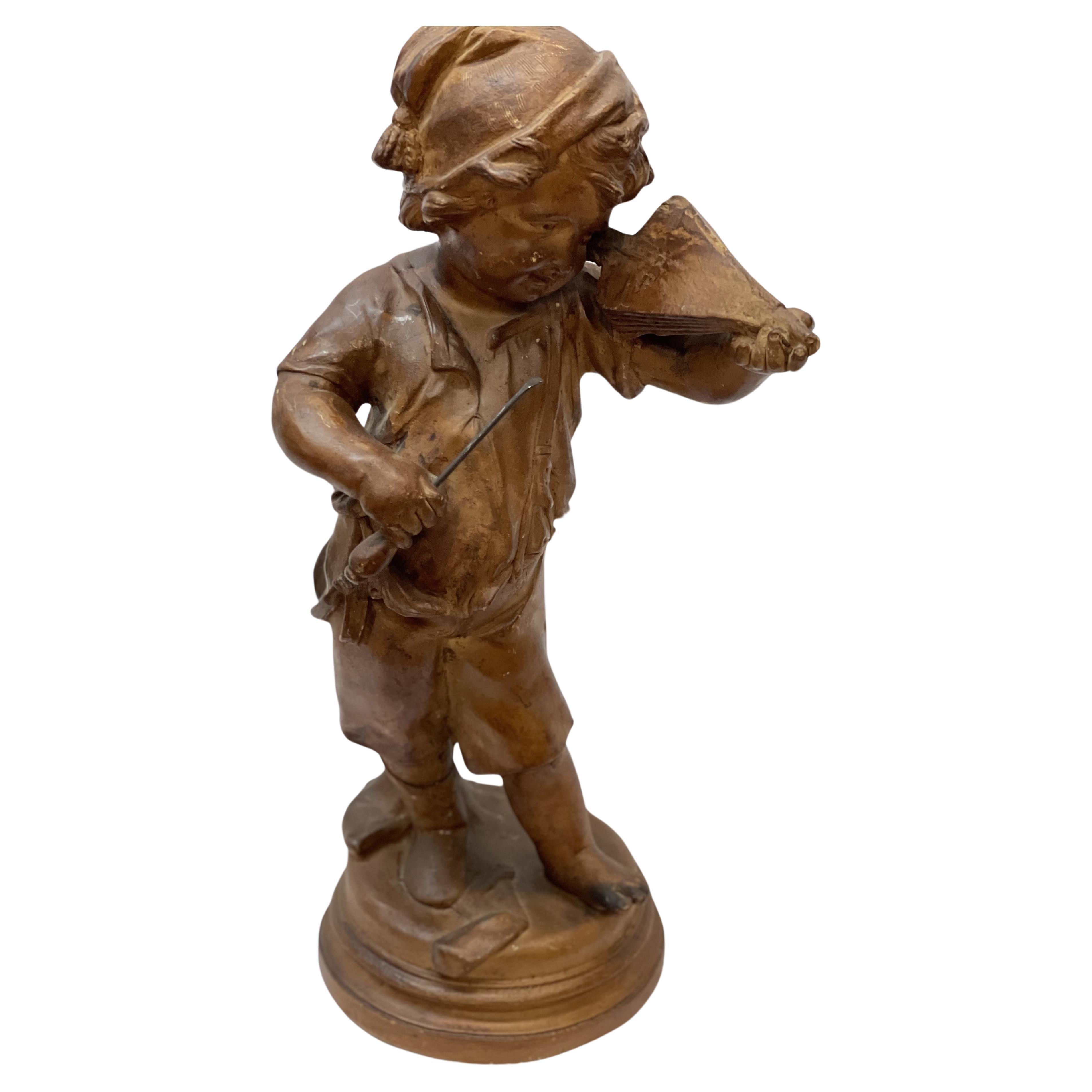 Figurine du 19e siècle représentant un jeune garçon avec un instrument de musique en terre cuite en vente
