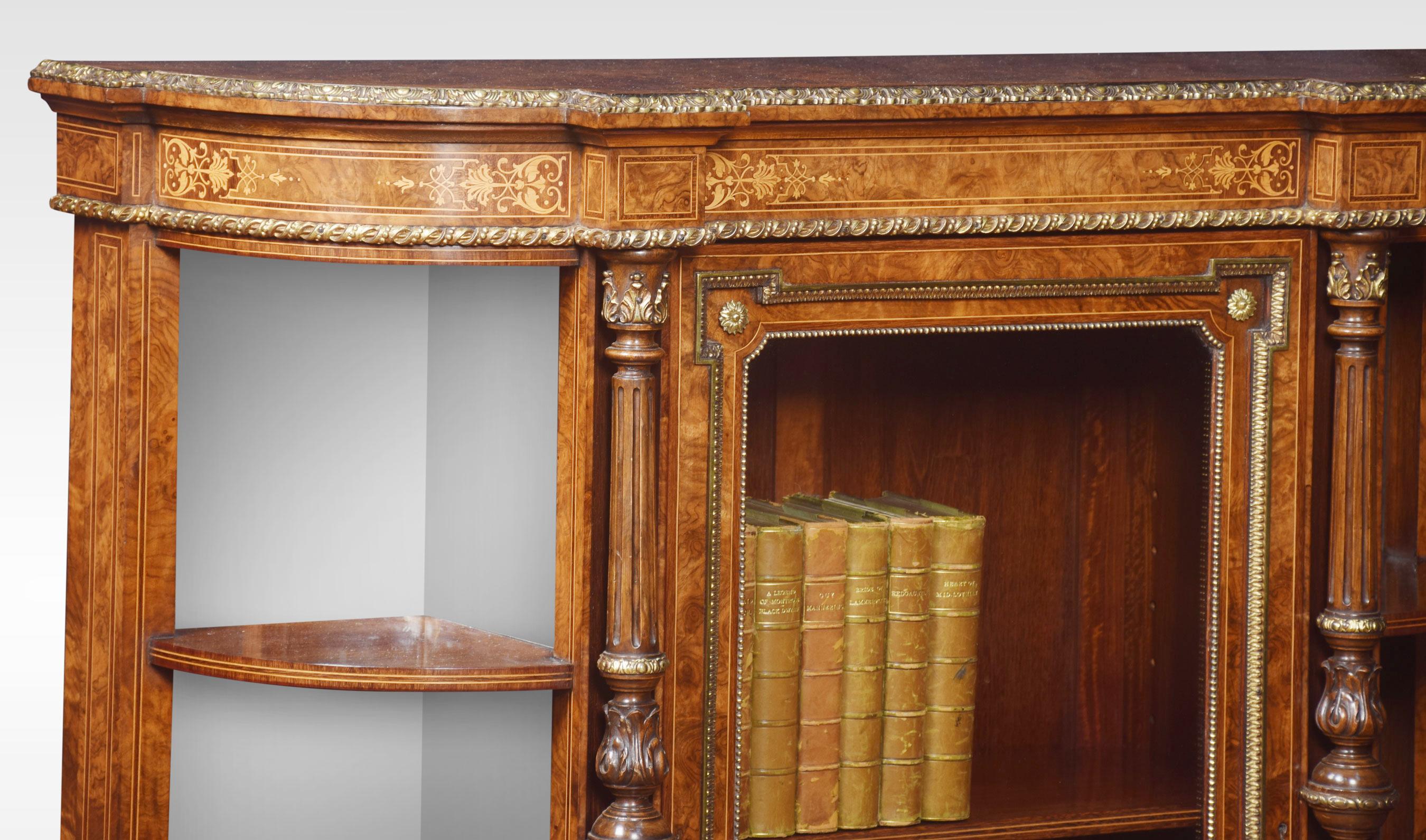 19th century walnut credenza, the well figured top above the inlaid frieze. To the central glazed panelled door flanked by two bays of shelves with mirrored back. Between ring turned and fluted pilasters with leaf scrolled gilt metal capitals.