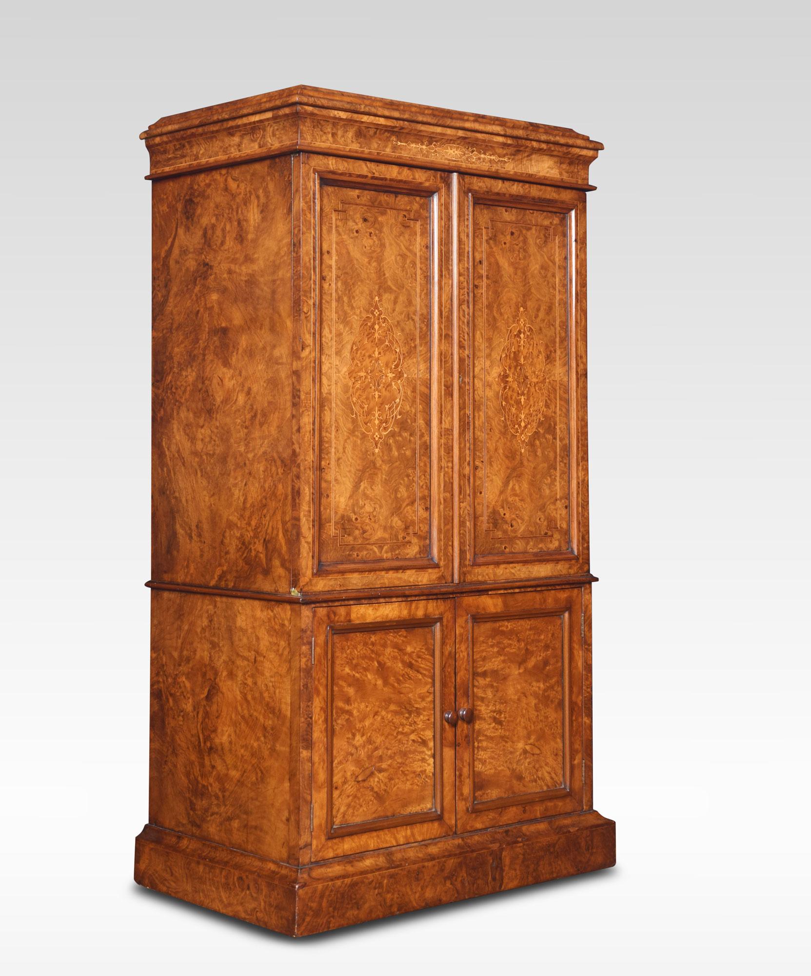 Walnut music cabinet the well figured top with a moulded edge. Above two inlaid panel doors opening to reveal a fitted shelved interior. To the base with two shorter panelled doors enclosing four dividing panels. All raised up on plinth