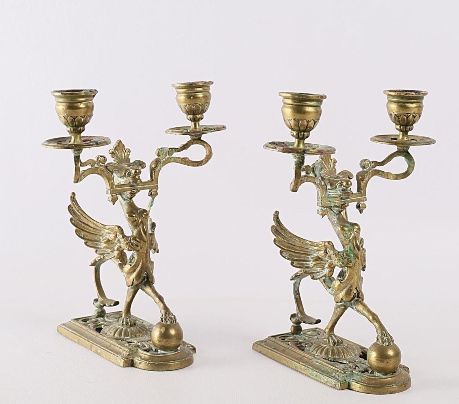 Fine pair of gilded metal candleholders with two arms of light, representing a chimeras with long wings poses on a balls.
France, circa 1870.