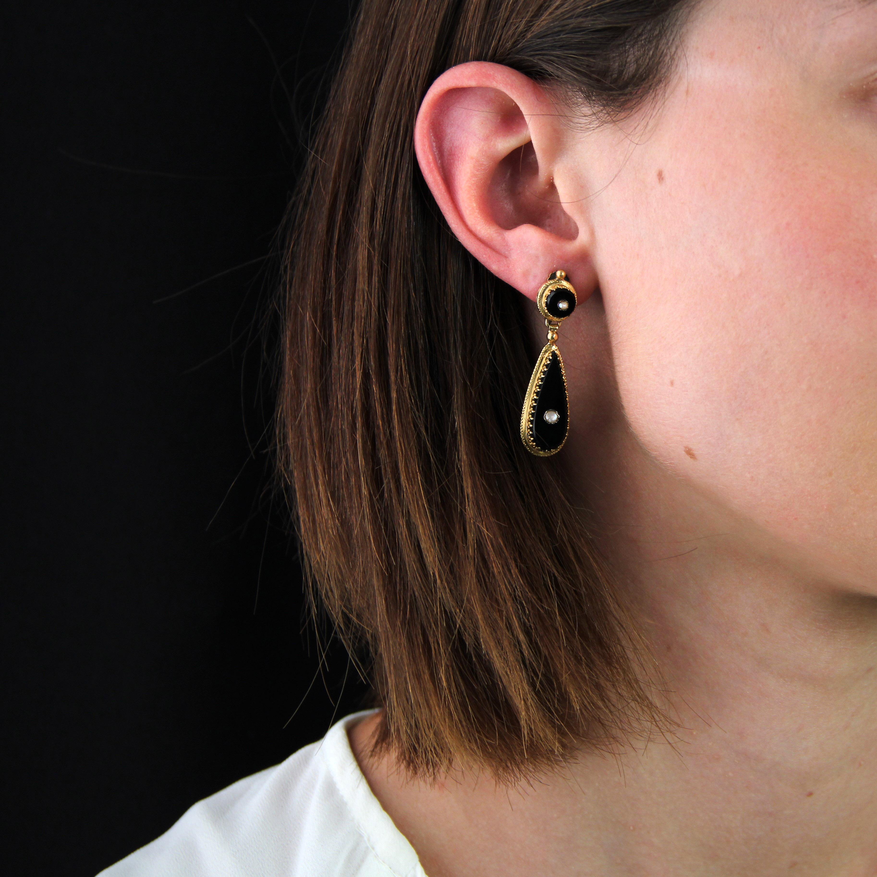For non-pierced ears.
Earrings in 18 karat yellow gold.
A pair of earrings featuring an onyx disk centered by a fine half-pearl held in place by lily flower claws. The same pear-shaped motif is attached as a pendant. The attachment system is