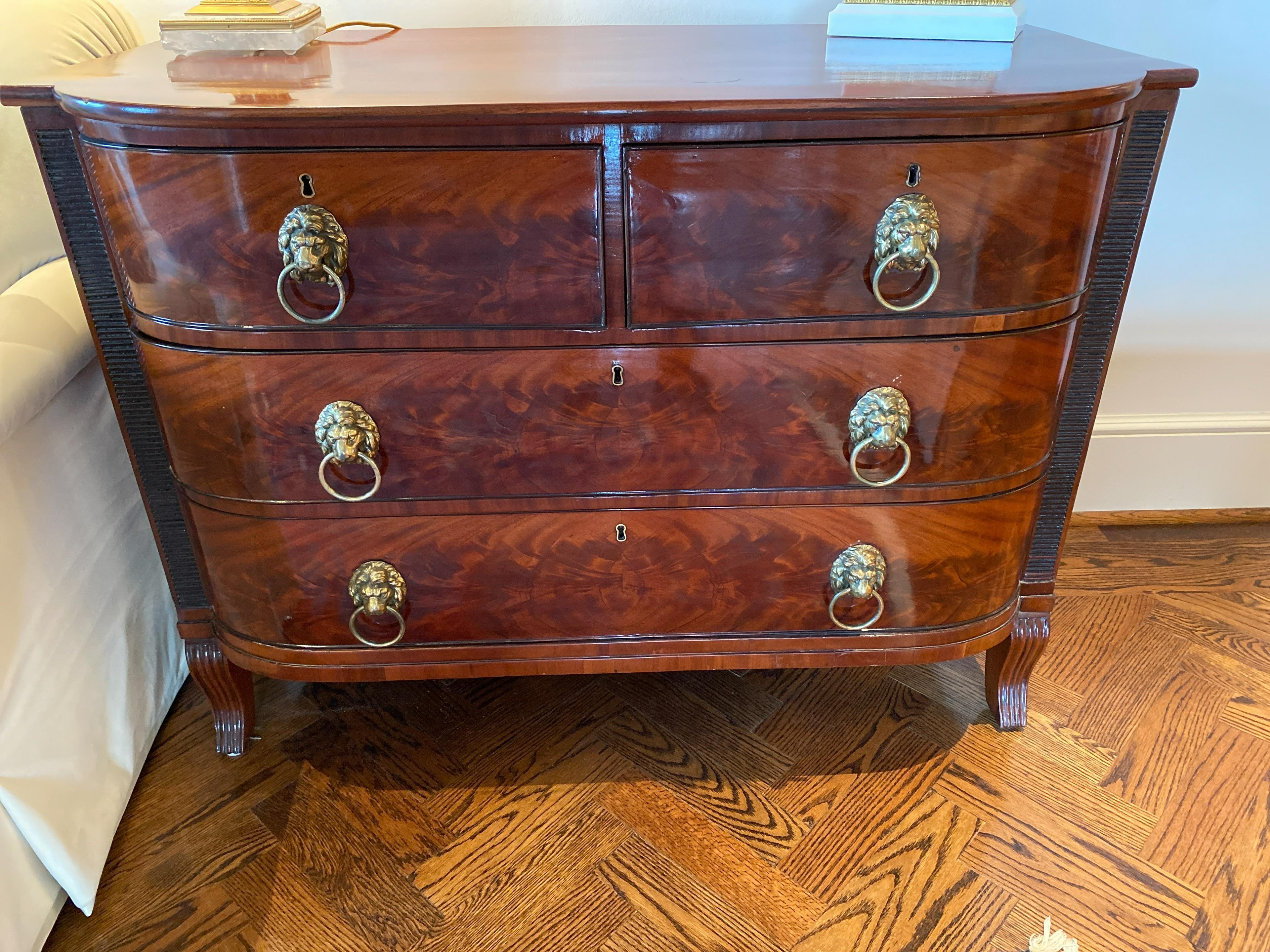 Beautiful and fine 19th century English Regency flame mahogany commode with brass Lions head pulls. Reeded carved detailed sides. Beautiful rich patina.