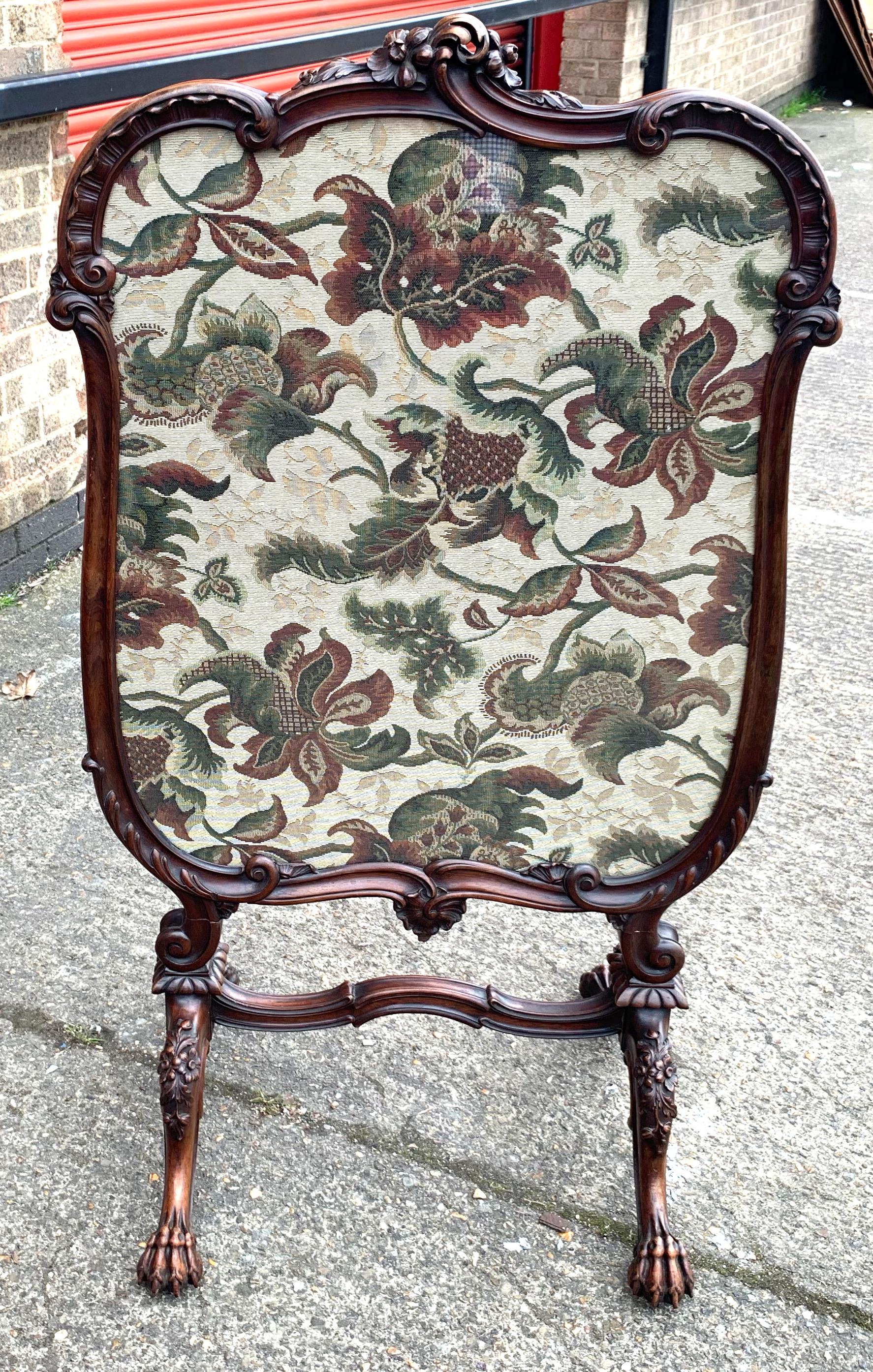 A fine Walnut framed fire screen with woolwork Tapestry screen. Early 19th century. The carved framed enclosing a panel handworked with flowers and foliage. On scroll legs with conforming cross stretcher terminating in paw feet.