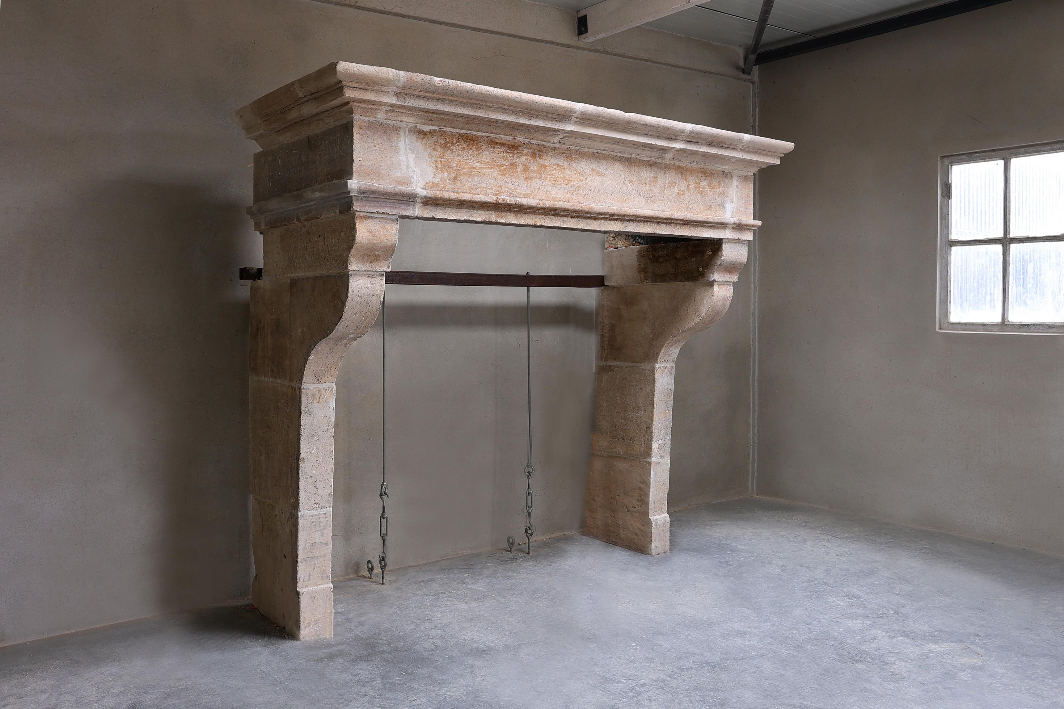 Beautiful robust castle fireplace of French limestone in style of Louis XIII. This stately mantle surround has a wide front section, beautiful lines and half-bent legs. The warm color scheme and beautiful shape and appearance make this a fireplace