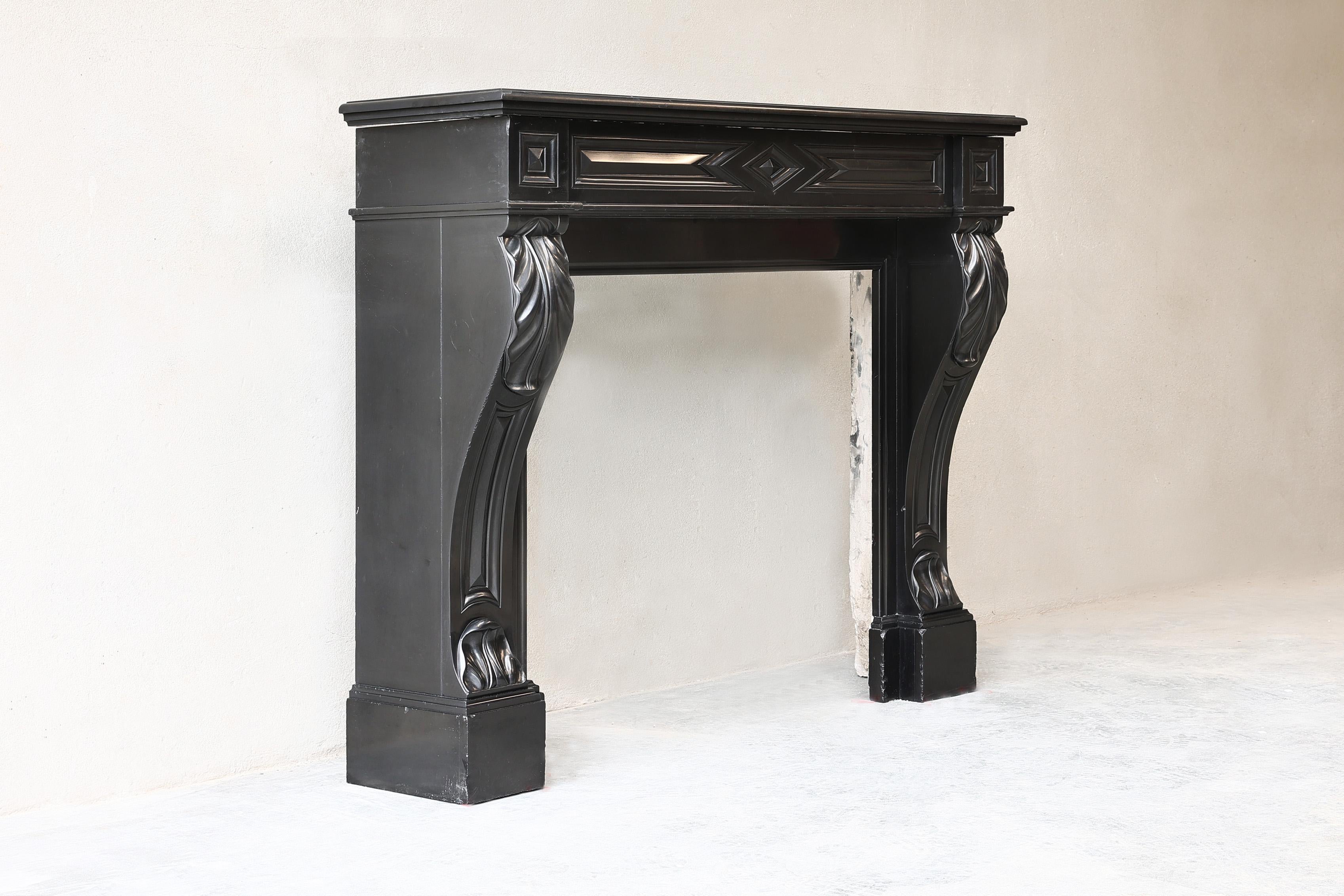 Beautiful antique mantelpiece made of Noir de Mazy marble with beautiful curves and ornaments. This mantelpiece dates from the 19th century and is in the style of Louis XVI. A black mantelpiece always looks chic and is certainly applicable to this