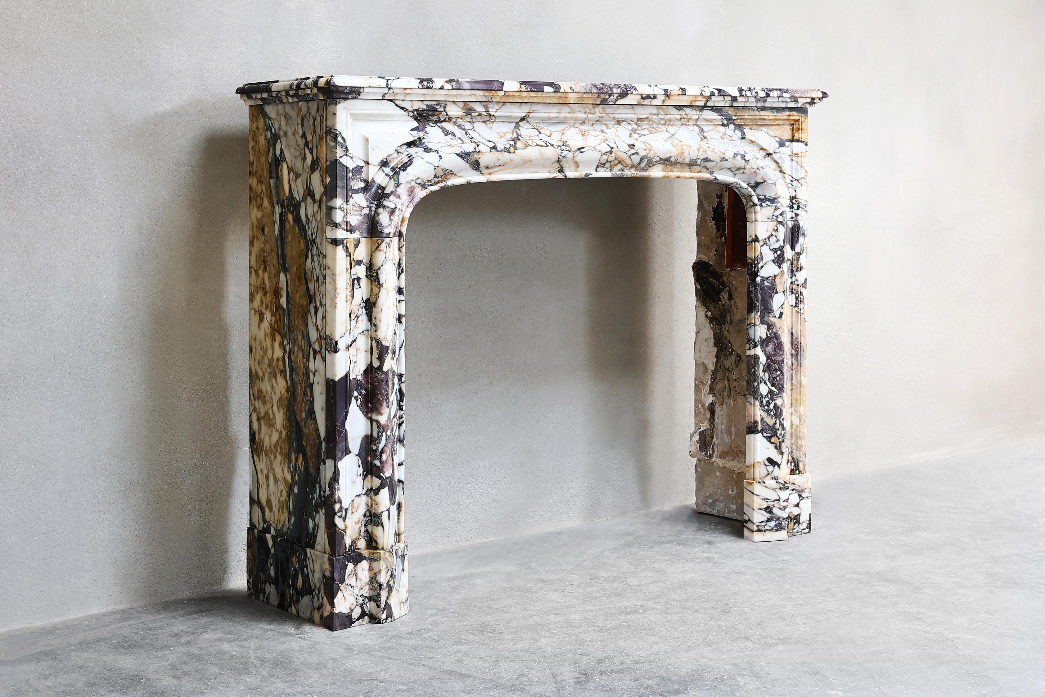 Beautiful antique fireplace of Breche marble from the 19th century in the style of Louis XIV. This special marble fireplace is colorful and sleek! The combination of this marble type and shape creates a unique fireplace.