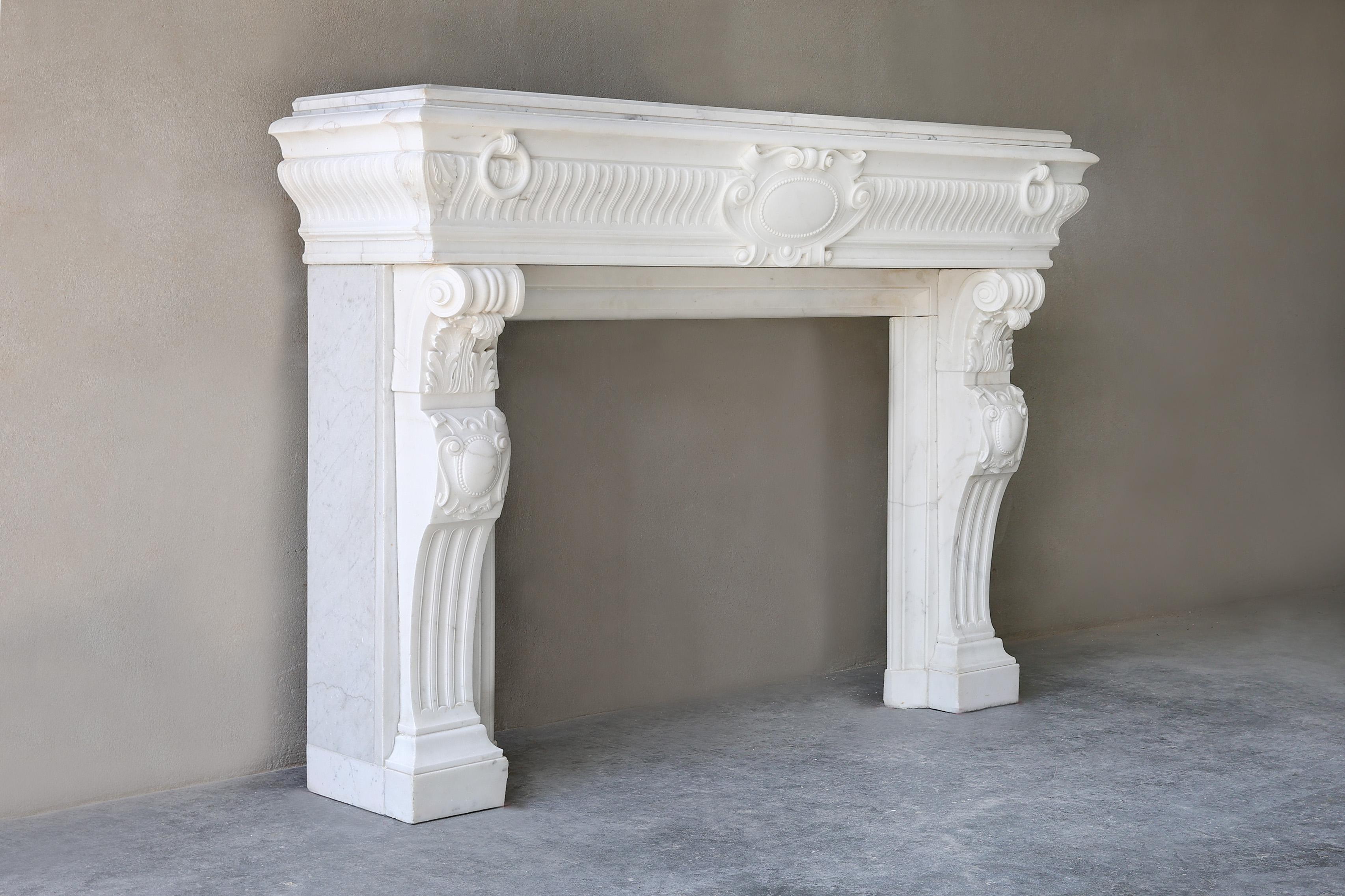 Beautiful authentic fireplace of Carrara marble from Italy. This 19th century fireplace is richly decorated with ornaments and flutes in the front part and on the legs. A colossal mantle with a chic look. This antique fireplace is in the style of