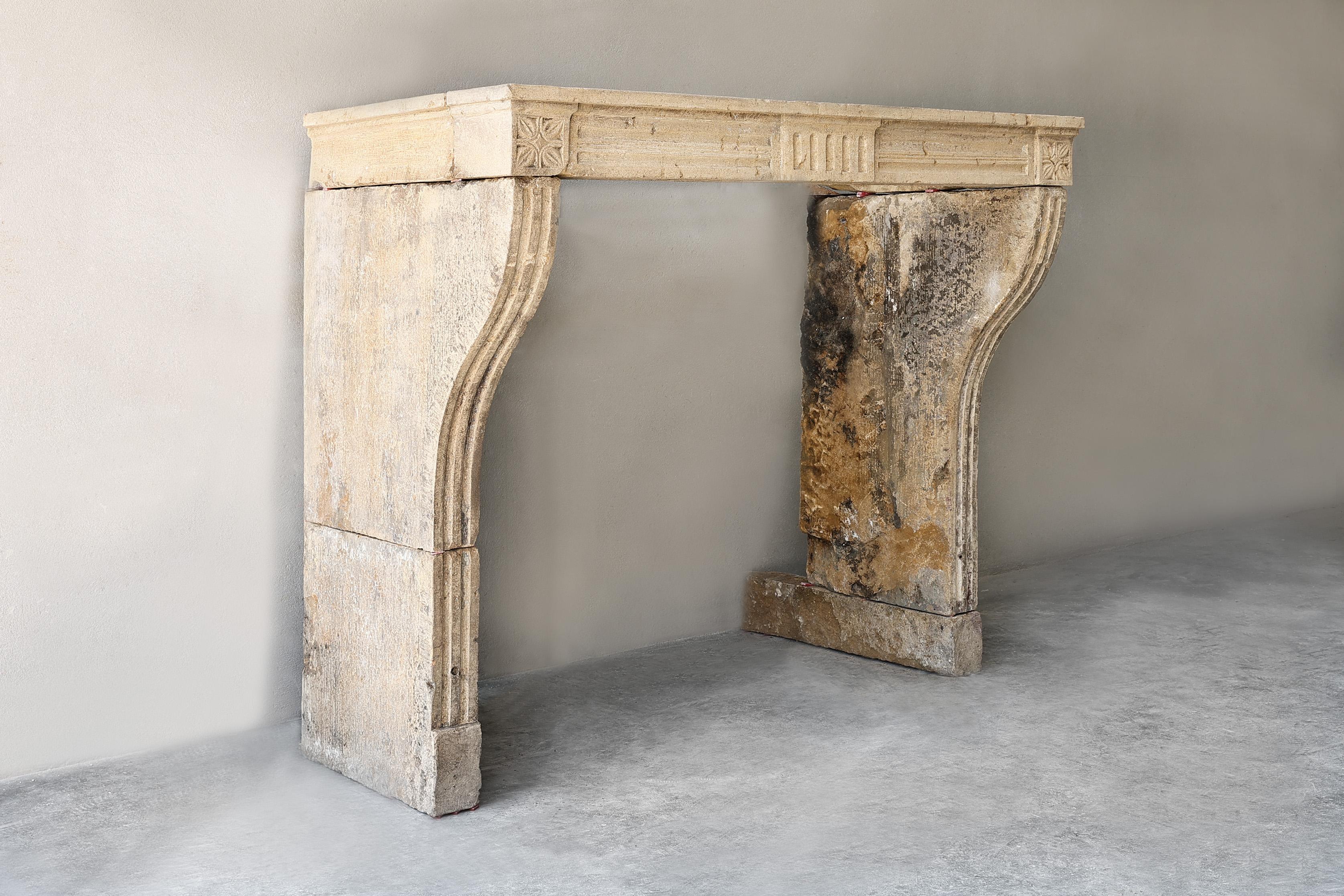Antique French limestone fireplace from the 19th century! A rustic, slender fireplace with few ornaments, but with beautiful lines. The front part is provided with flutes that also continue on the legs. The legs are slightly curved and the warm