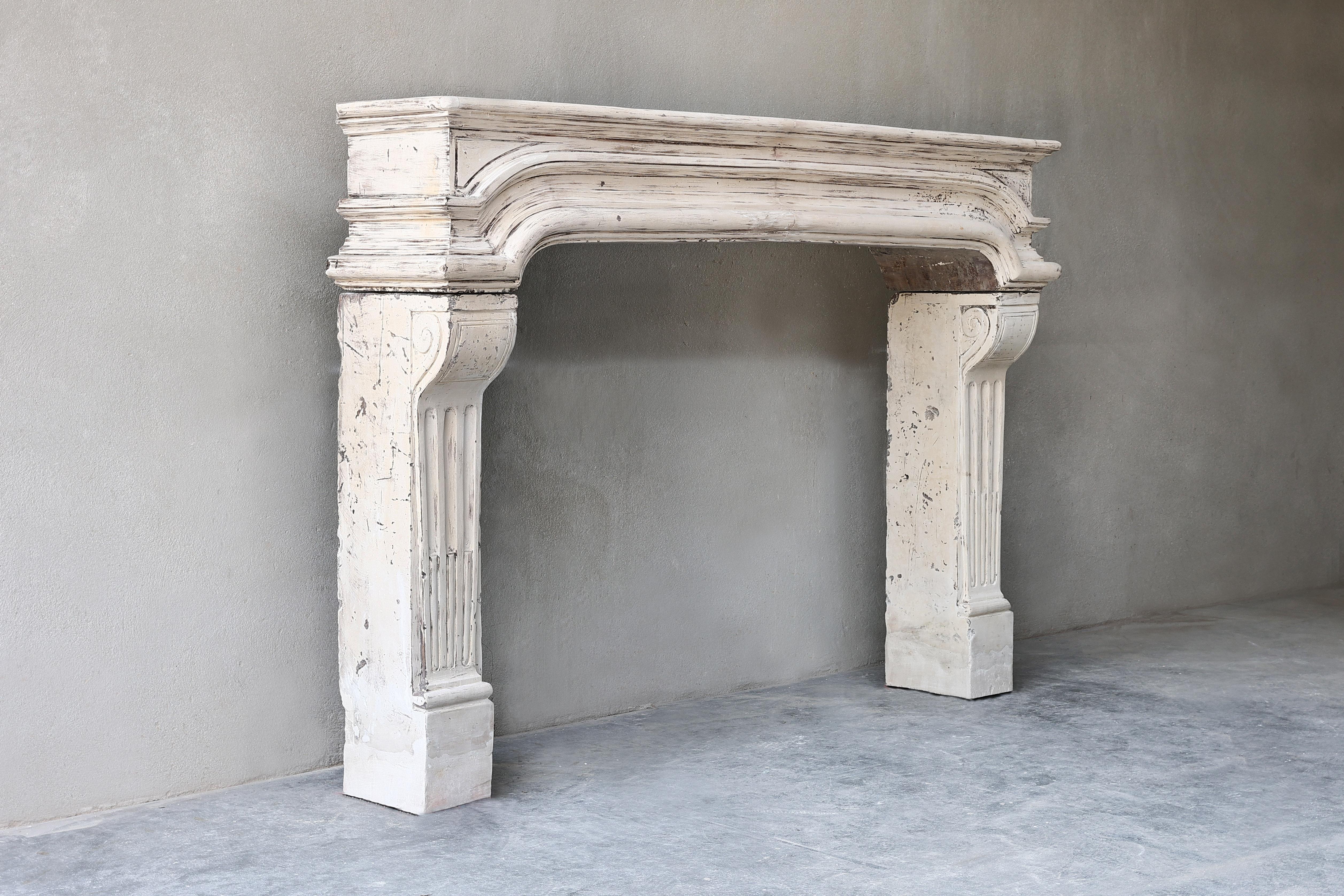Special antique fireplace of French limestone. A unique item within our collection due to the unusual shape, beautiful lines and fluting on the legs. 
We can offer this fireplace for an attractive price as the freeze/shelf has been broken.
We have