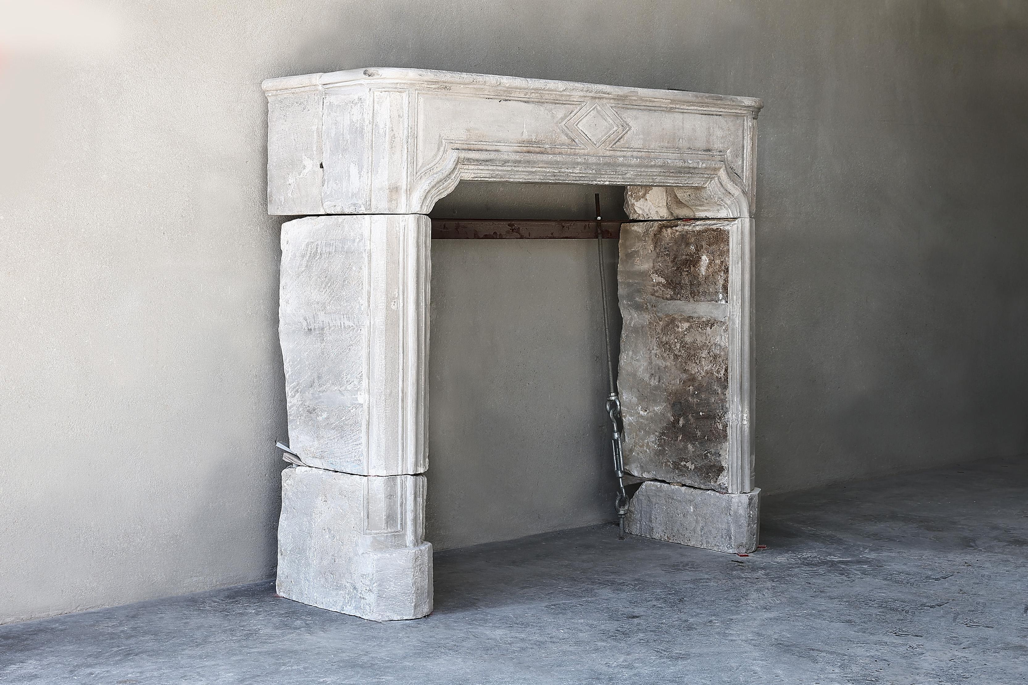 Beautiful compact antique fireplace of French limestone from the 19th century in the style of Louis XVI. A fireplace with an ornament in the middle of the front part and beautiful lines. This fireplace can be used in different interiors.