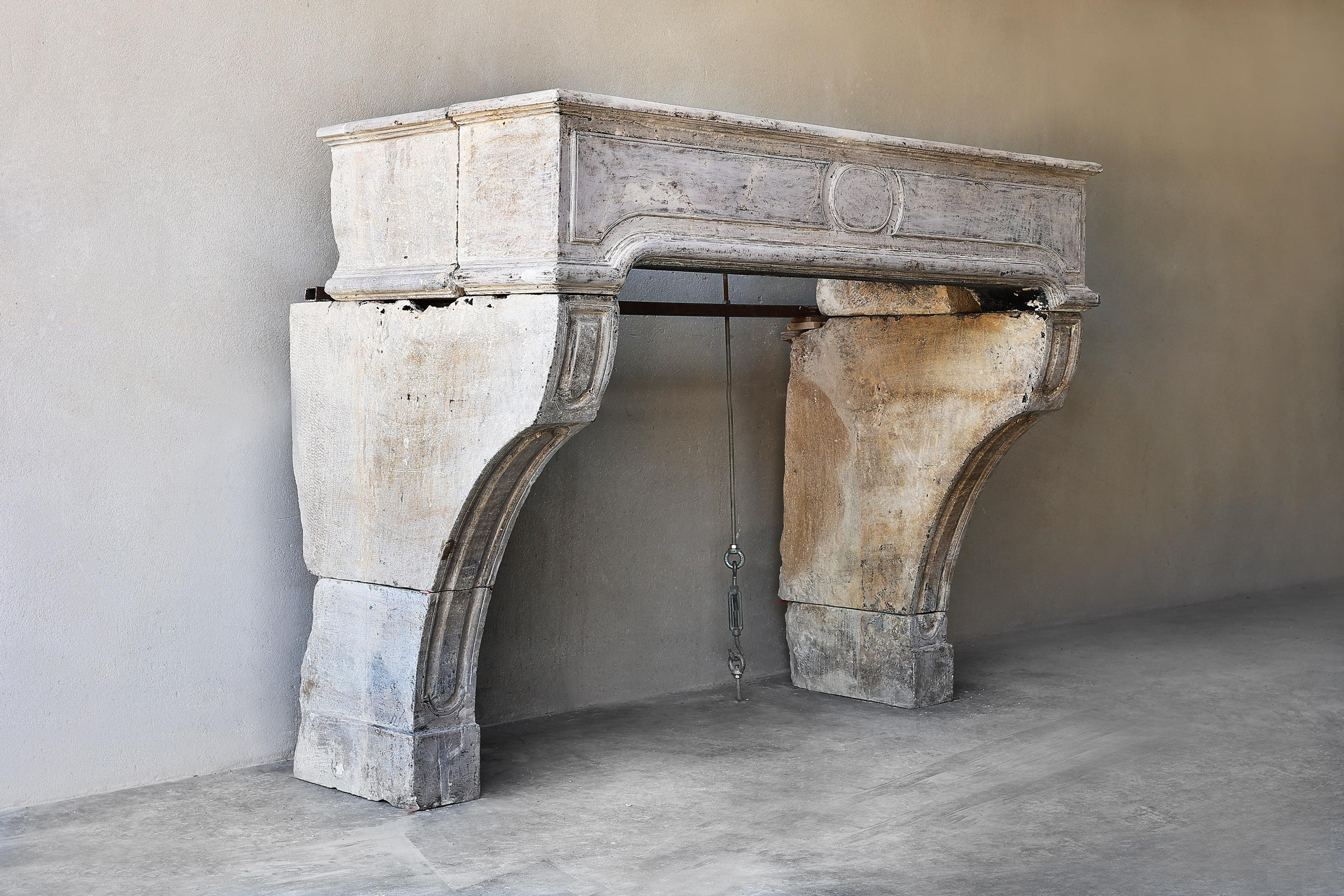 Beautiful French limestone fireplace in the style of Louis XV from the 19th century. A fireplace with a nice round ornament in the middle of the front part and beautiful cut lines in the legs of the mantle! This fireplace has a friendly appearance