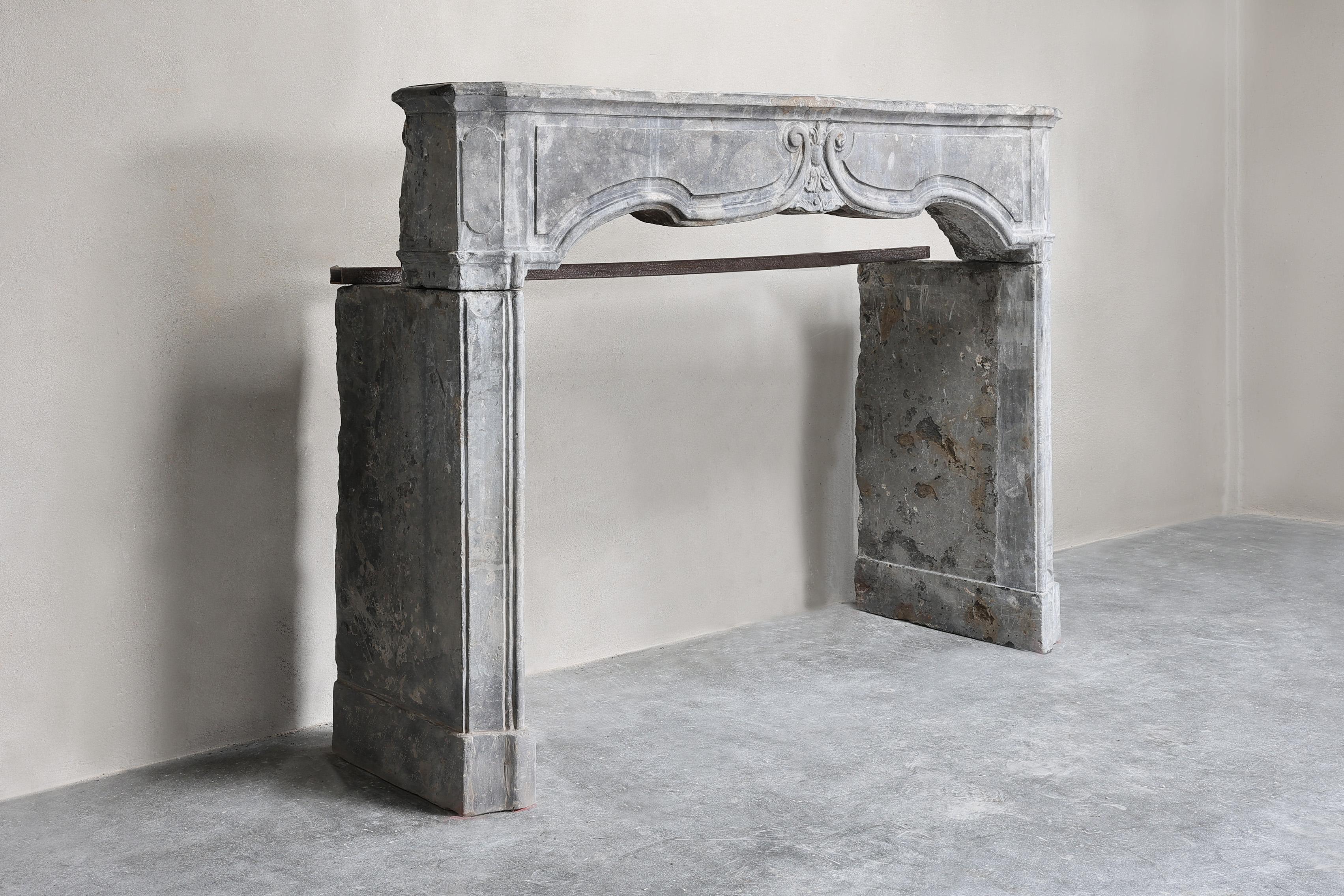 A beautiful antique mantelpiece, made of gray marble stone from the 19th century in style of Louis XV, exudes timeless elegance and historic charm. This antique fireplace mantelpiece is not only a functional element in an interior, but also a