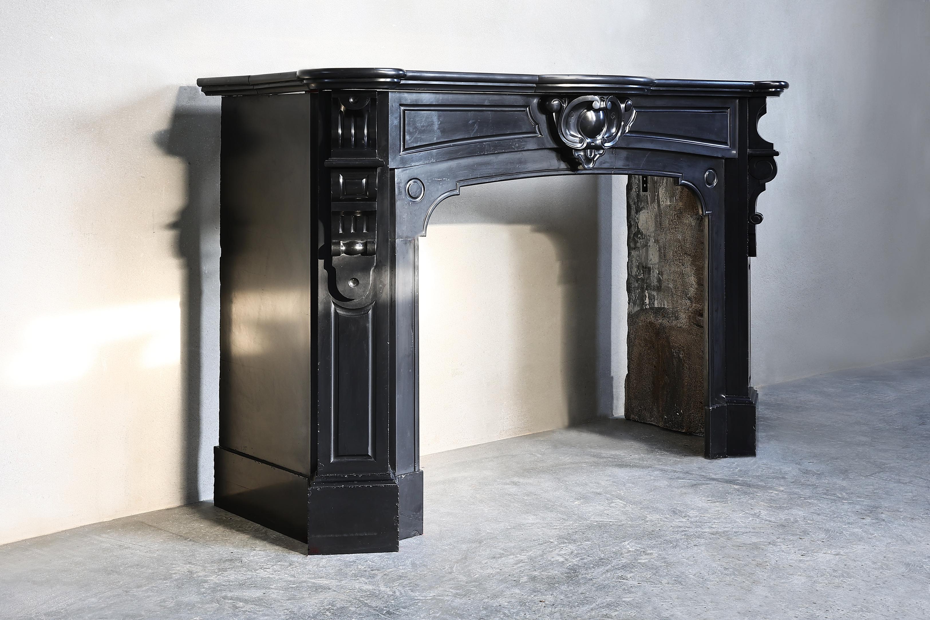 Very nice antique fireplace of Noir de Mazy marble from the 19th century. This fireplace is in the style of Louis XIV and has beautiful ornate ornaments incorporated in the fireplace! A graceful chic fireplace with appearance and allure that fits